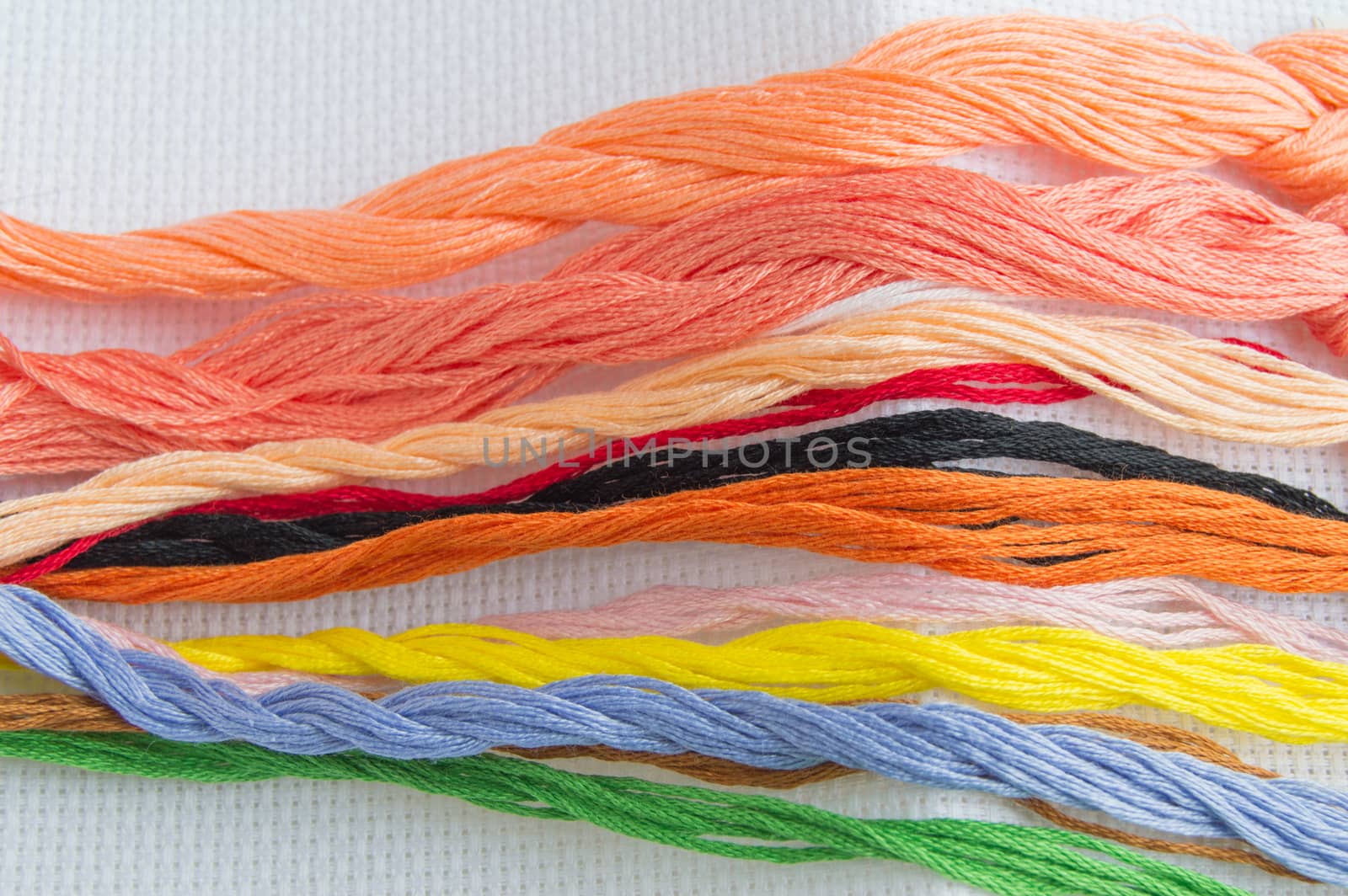 Bright colorful thread for embroidery thread on canvas. Handmade accessories on white background. Place for text, top view.