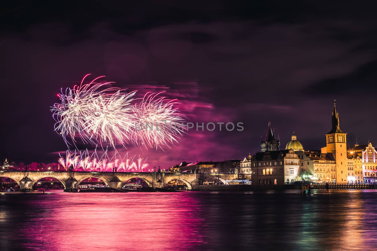 Beautiful fireworks above Charles bridge at night in Prague, historic center, Czech Republic, bautiful reflections in water.