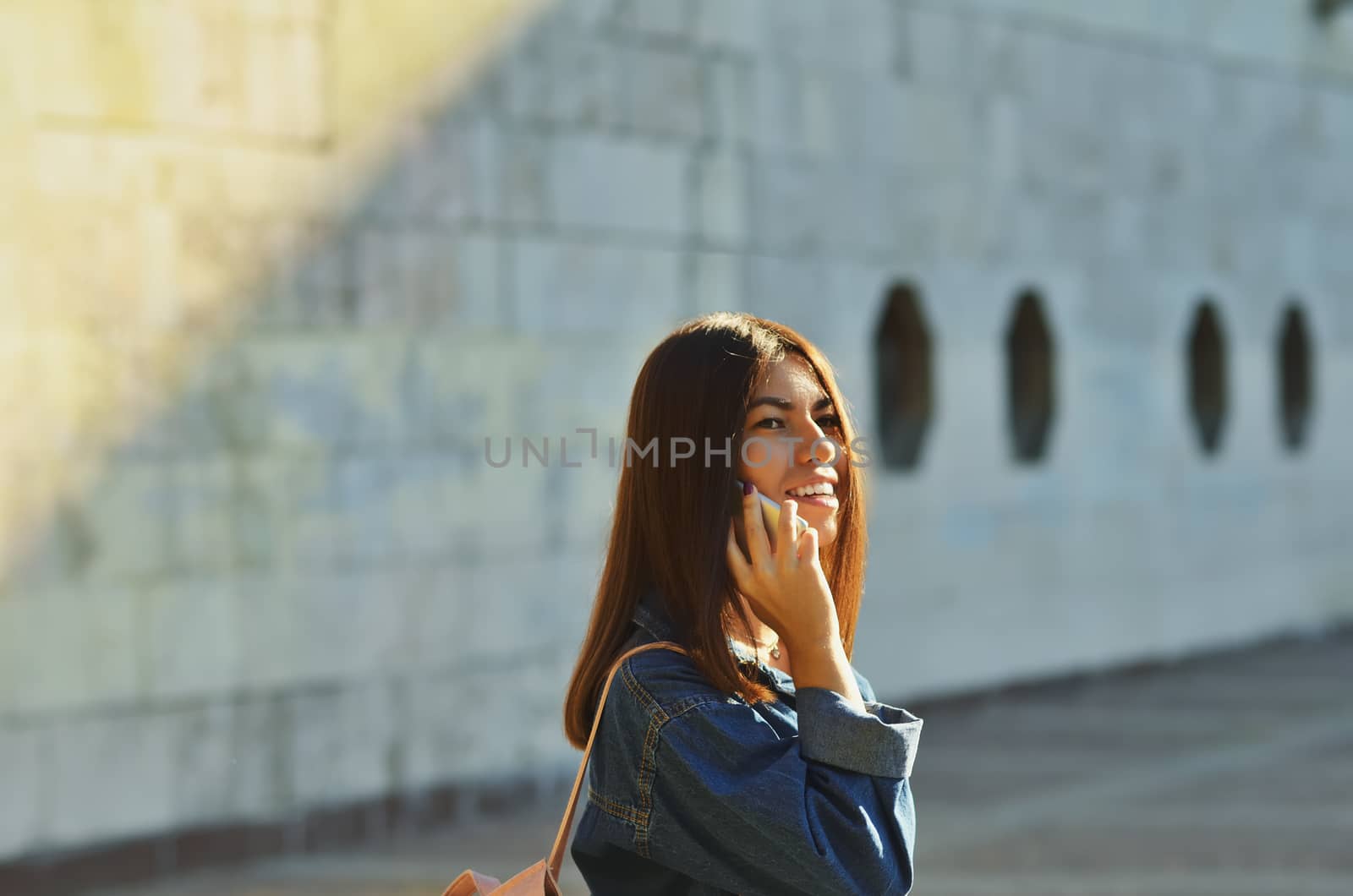 Young girl walking around the city on a Sunny day in the spring and talking on the phone