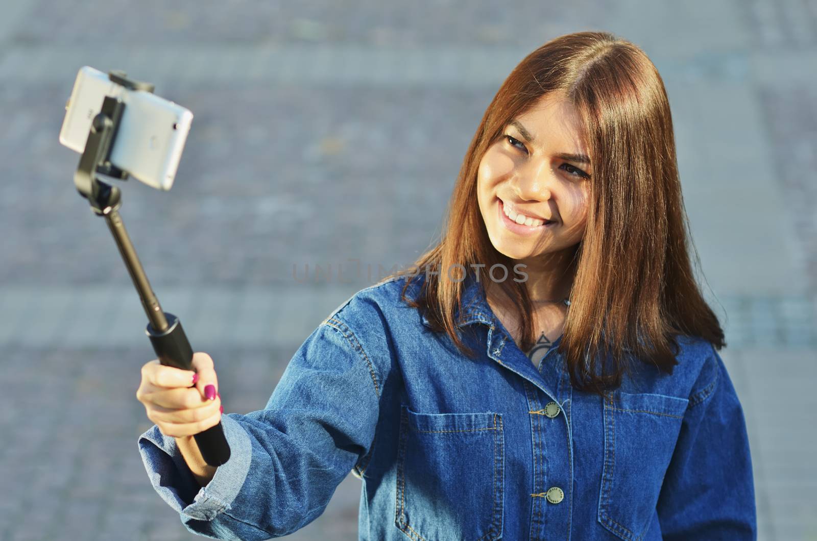 Brunette girl Asian looks in a denim suit takes a selfie and smiles