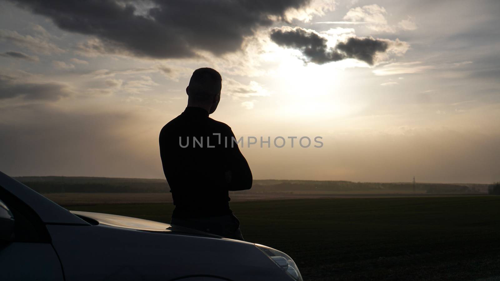 Silhouette of the man standing near to car and looking at a sunset by natali_brill