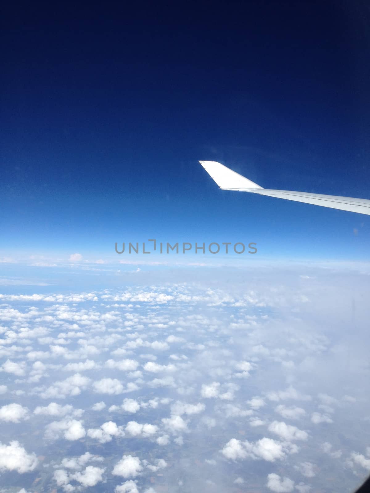 The view from the airplane on the wing, flying over the clouds. The concept of traveling by plane.