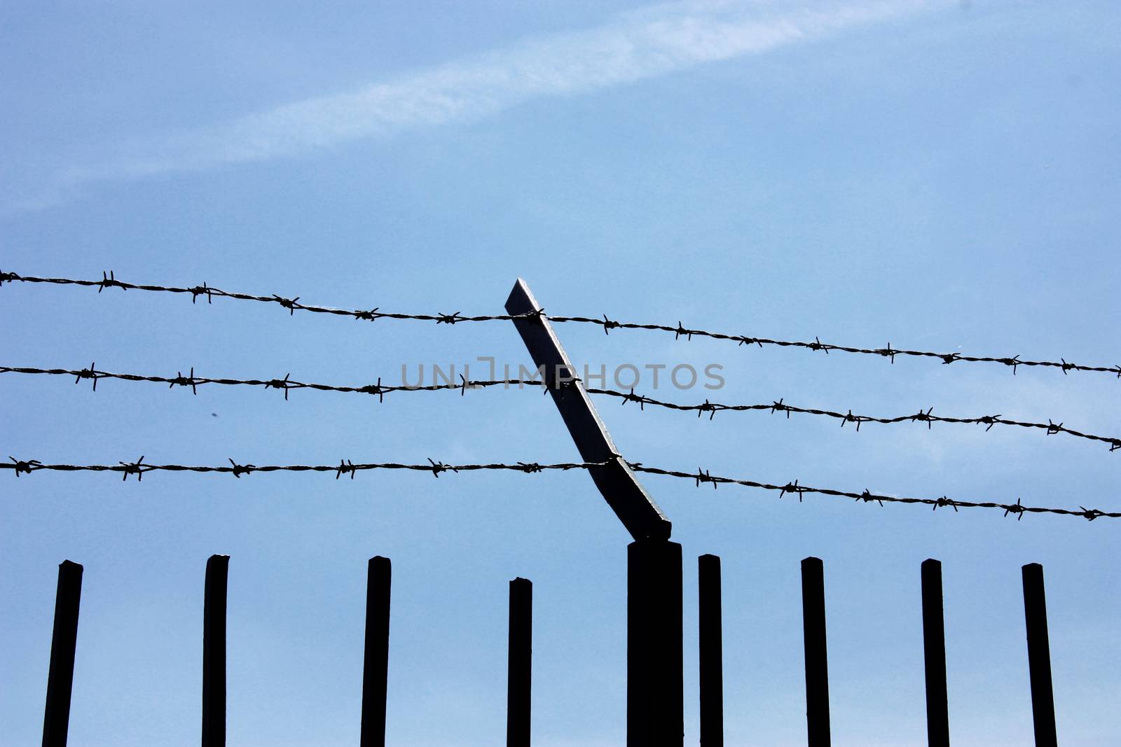 fence with barbed wire against the blue sky. Symbol of freedom of imprisonment.