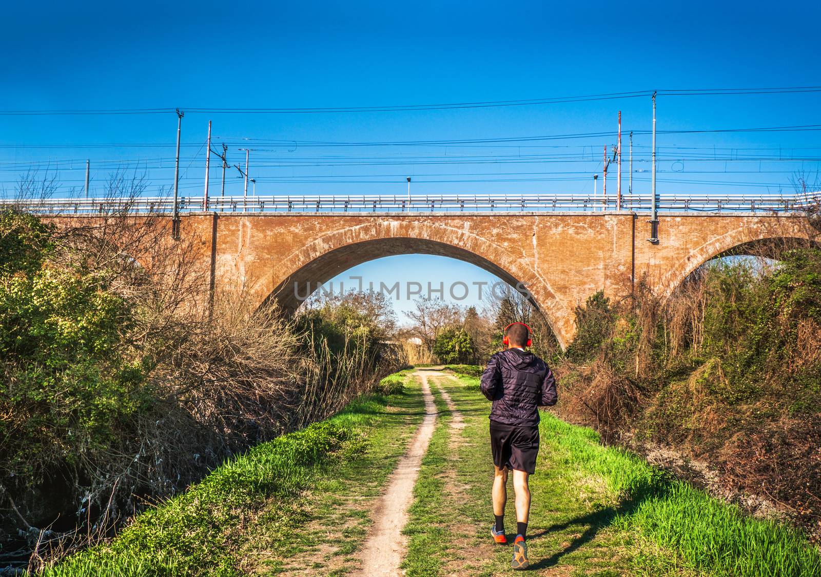 man jogging urban park bridge railway path trail in the city background .