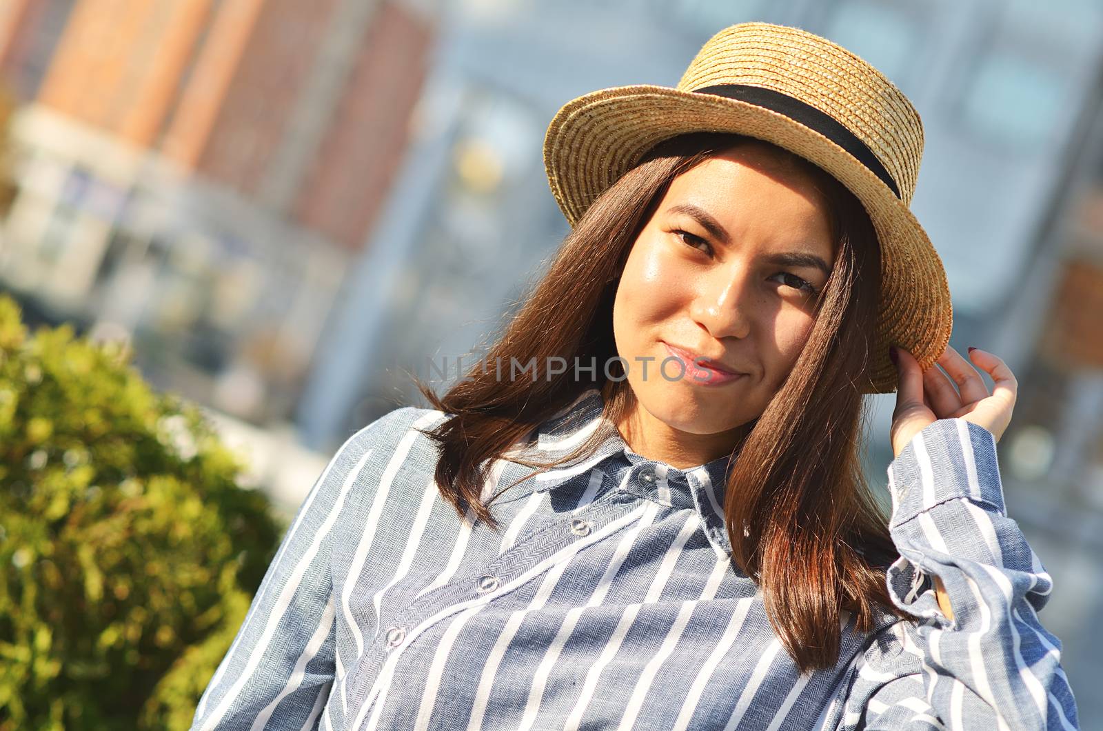 Portrait asian's girl is walking down the street in the city, in the hat near green bushes by xzgorik
