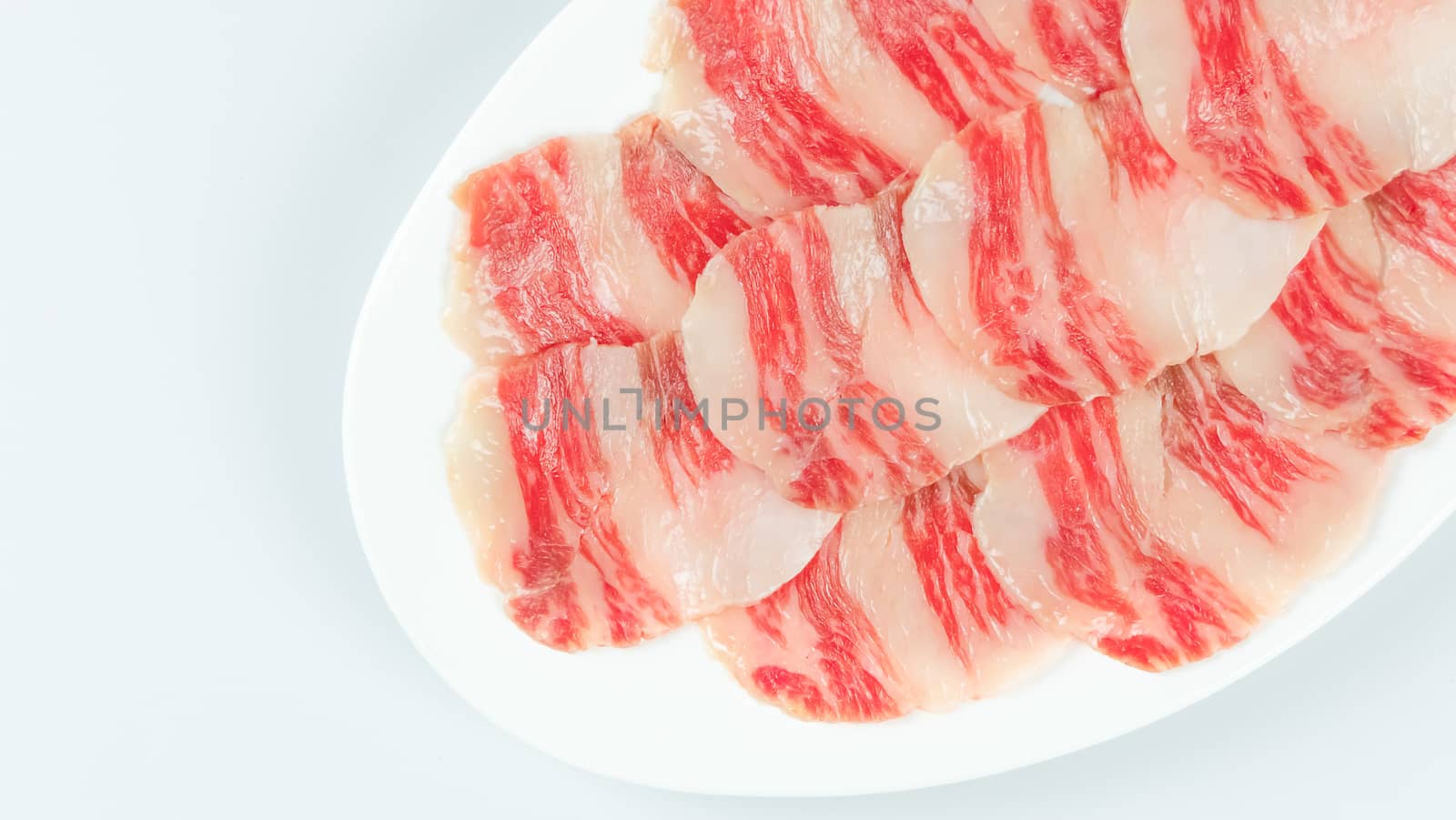 Top view of some raw beef on a plate over white background