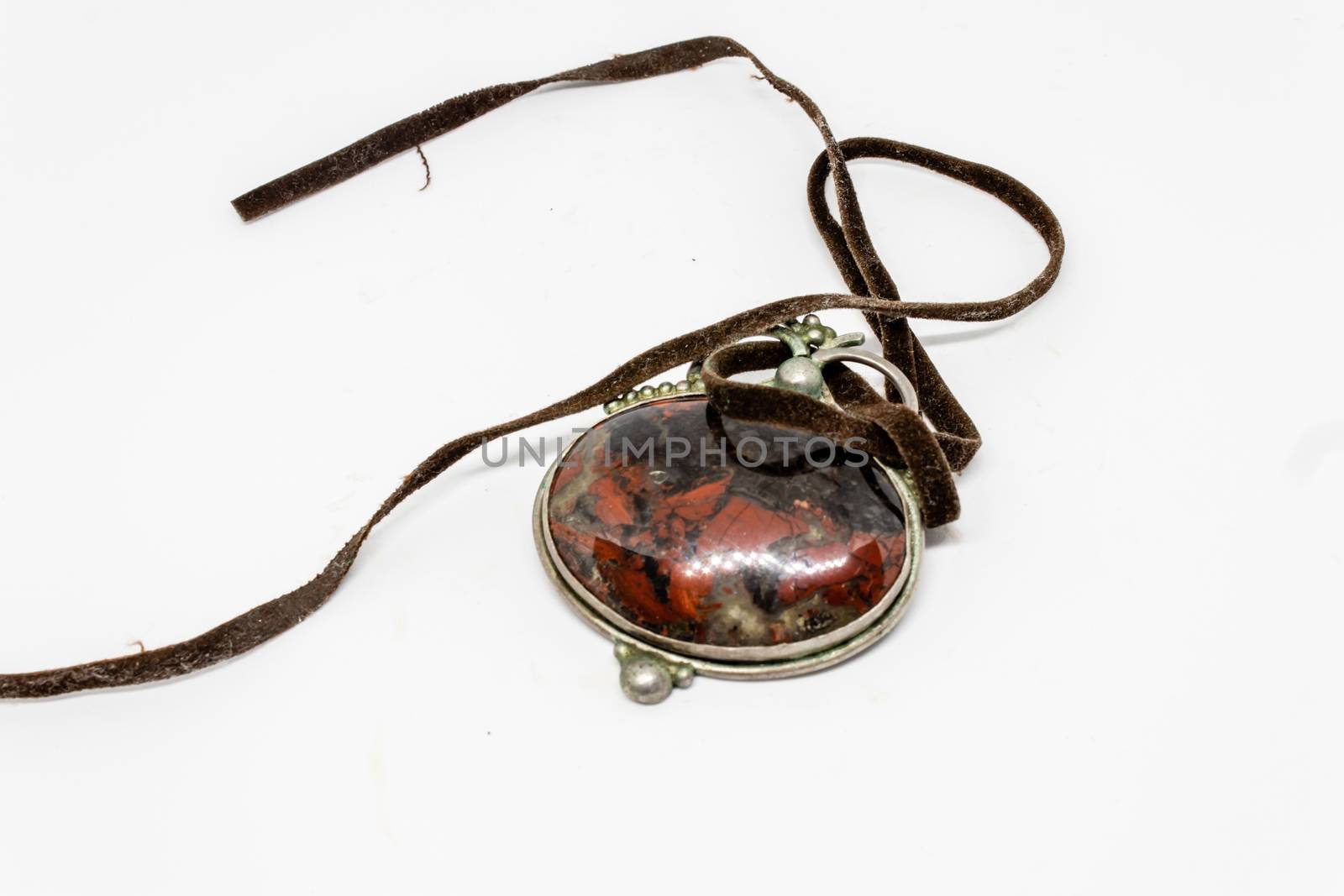 an isolated antique amulet closeup shoot with white background. With leather strap.
