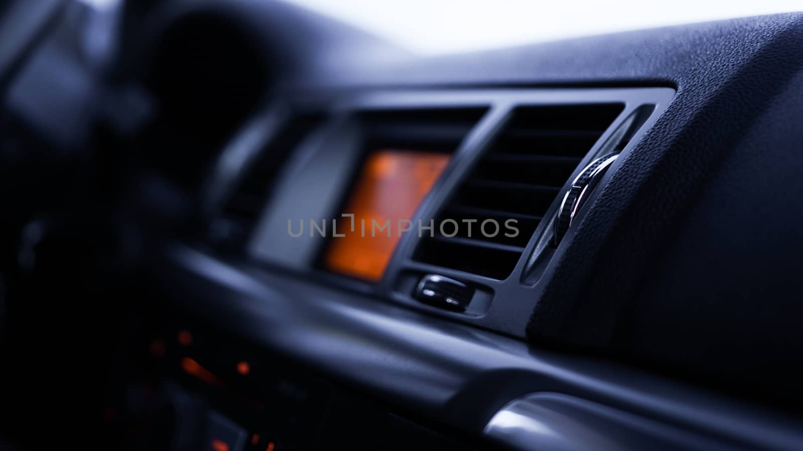 Buttons of radio, dashboard, climate control in car close up - black and orange