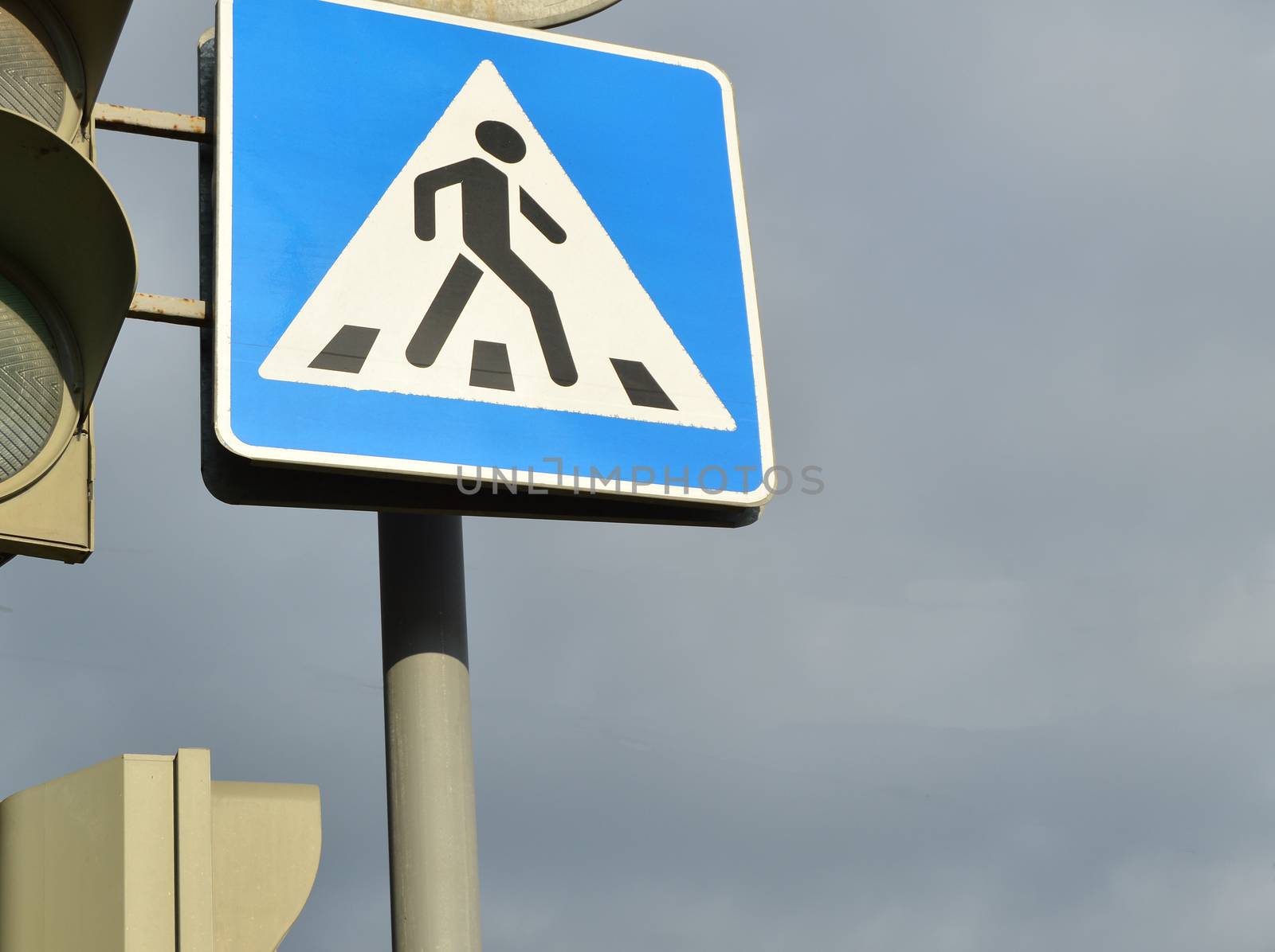 sign pedestrian crossing and traffic light on the background of the cloudy sky, the concept of road safety.