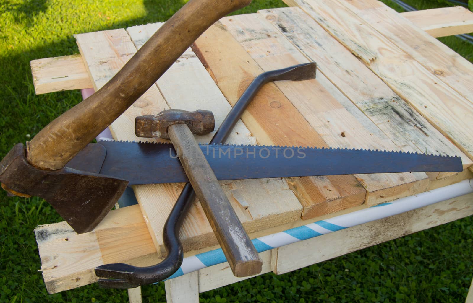 building tools hammer, axe, hacksaw frame, lie on the light boards in the garden.