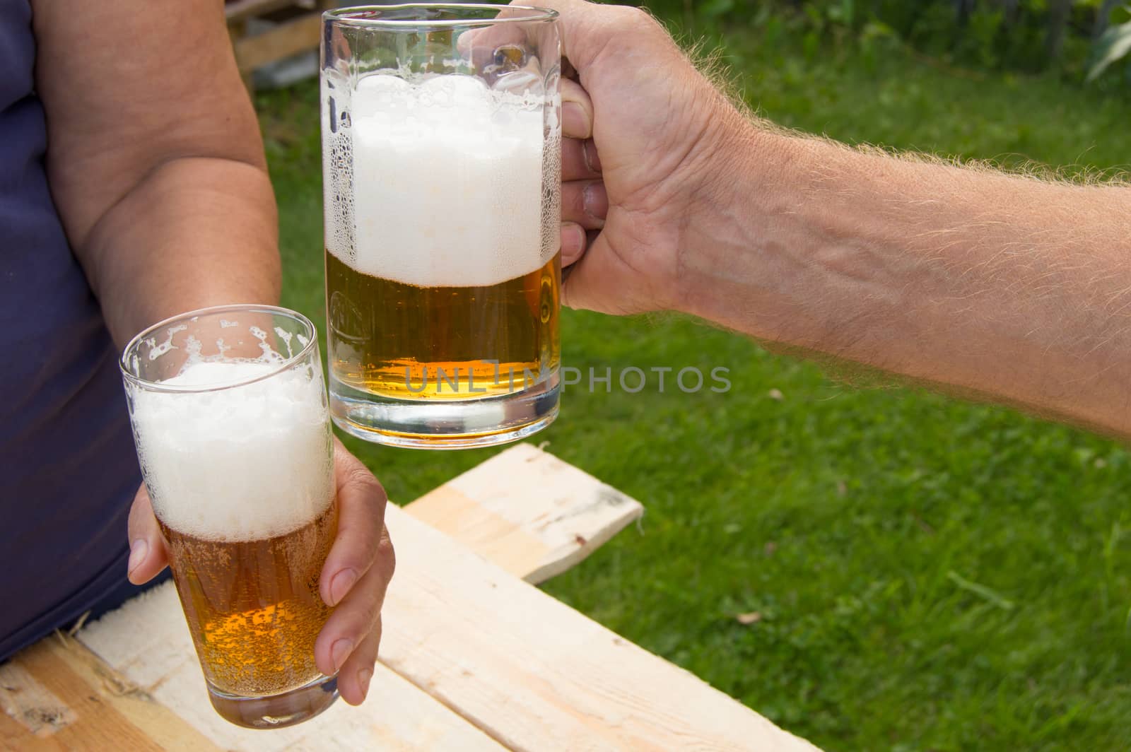 hands holding glasses with beer, chips and sausages lying on a light wooden boards, people relax in the weekends, Octoberfest by claire_lucia