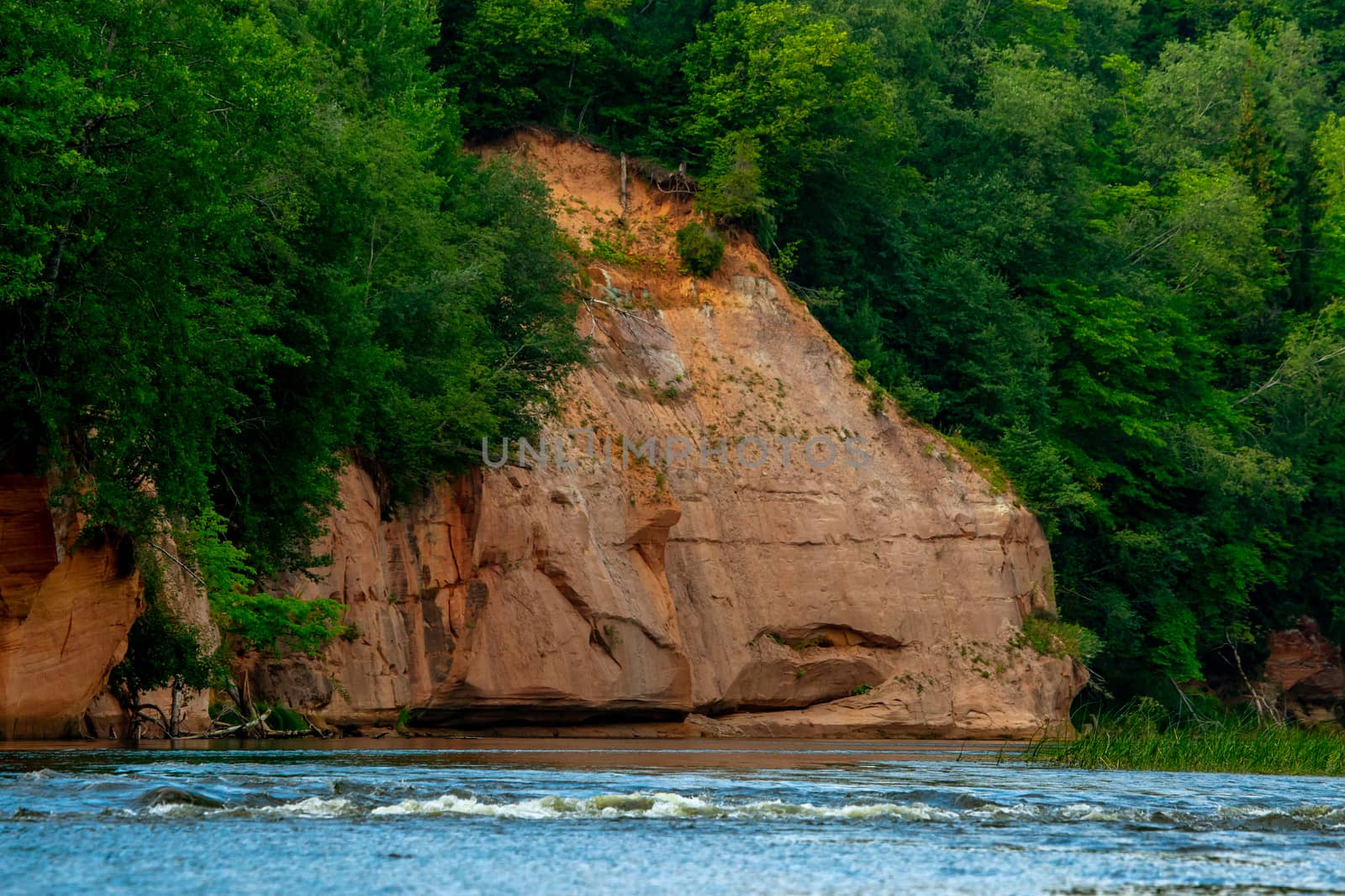 Red sandstone cliff on coast of the river  by fotorobs