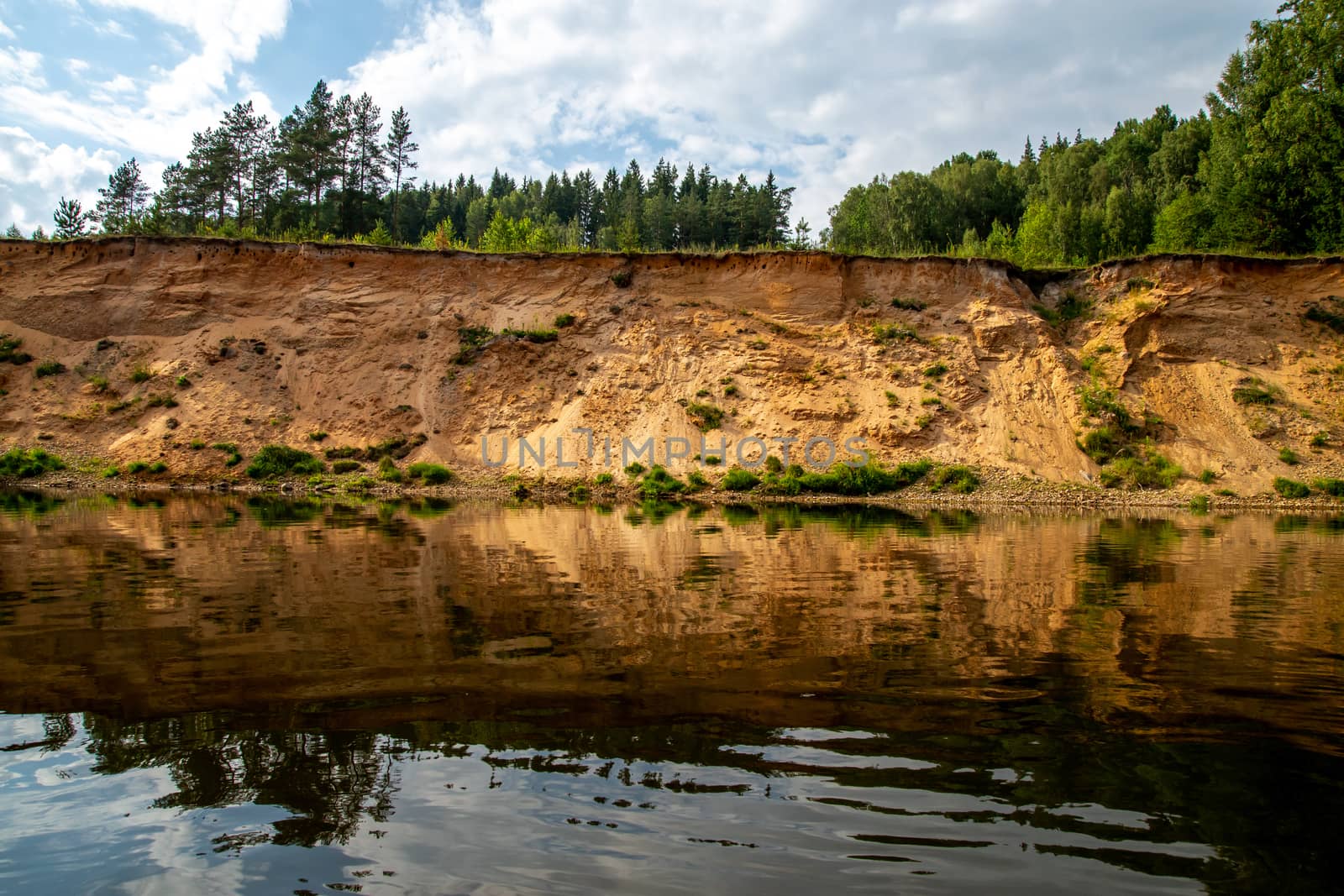 Landscape with cliff near the river Gauja, trees and sky reflection in water. The Gauja is the longest river in Latvia, which is located only in the territory of Latvia. 