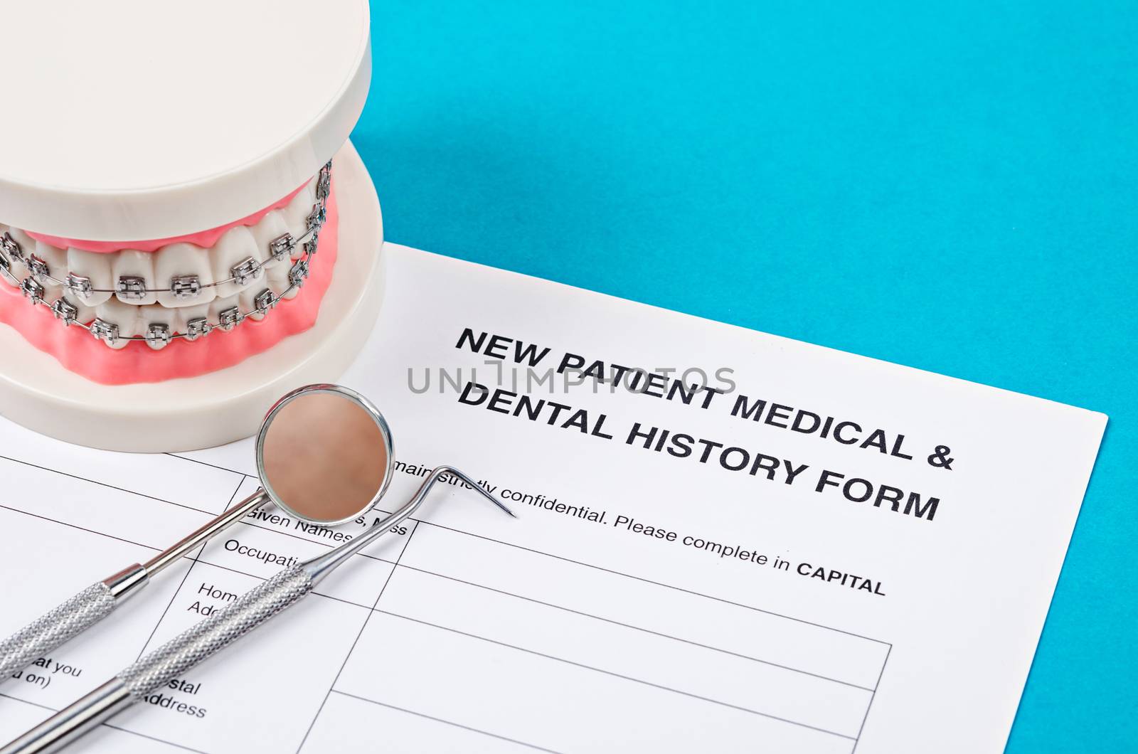 New patient medical form with model tooth and dental instruments. Dental health and teeth care concept.