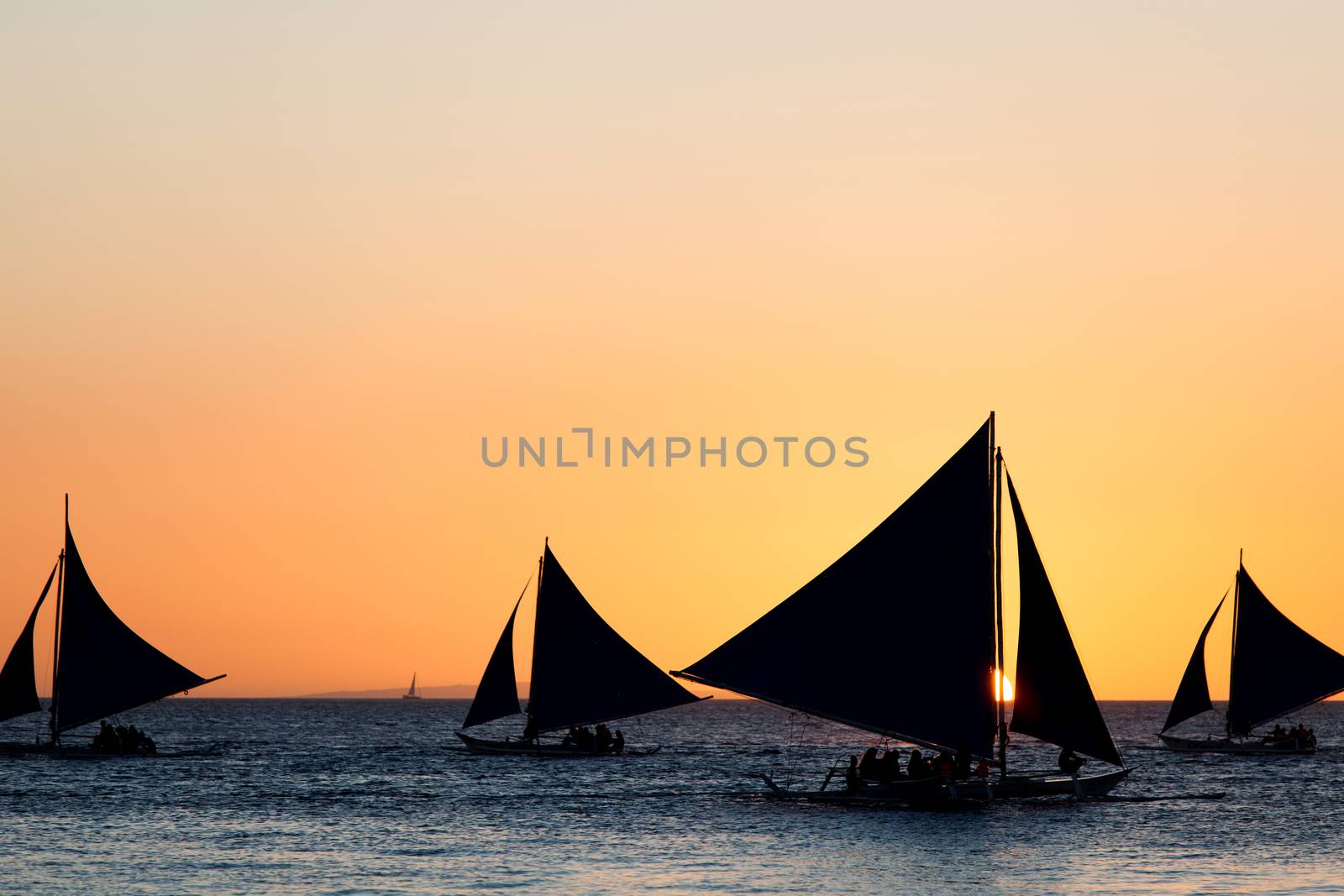 Sailing boats silhouette at orange sunset background