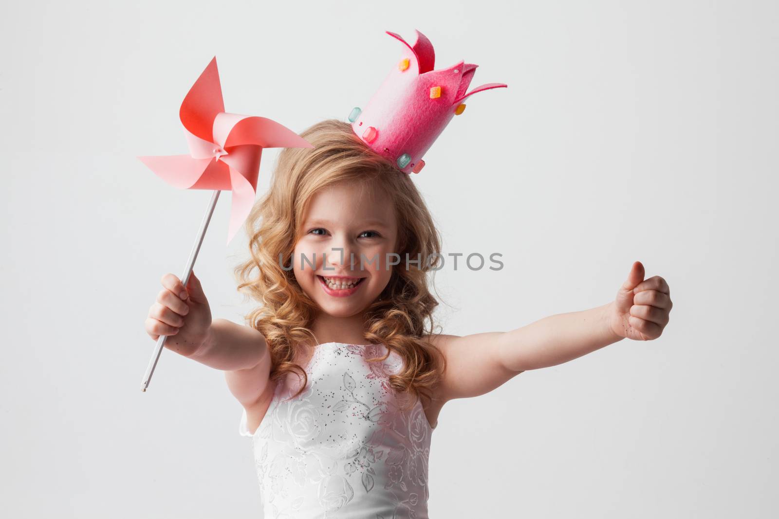 Beautiful little candy princess girl in crown holding pinwheel and smiling