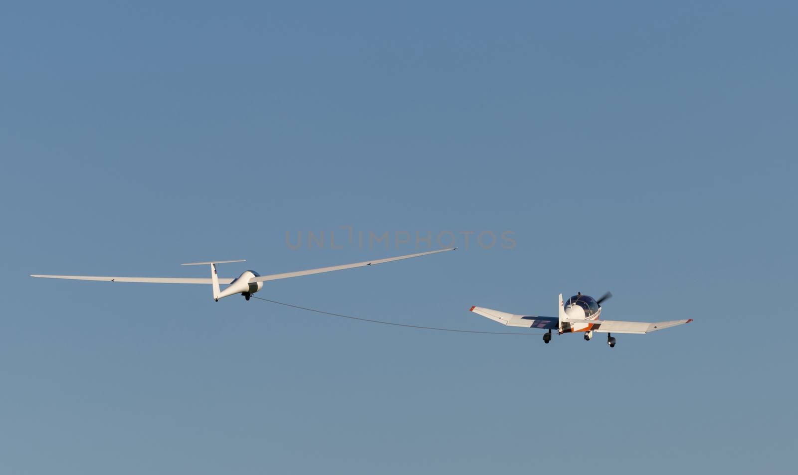 White modern glider which is increased by a small motorized sport airplane
