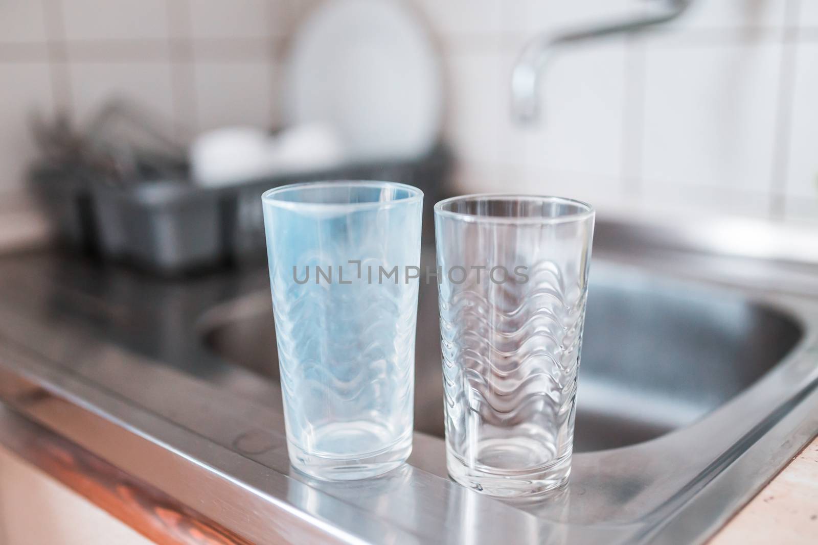 Dirty and clean glass cups on a kitchen sink.