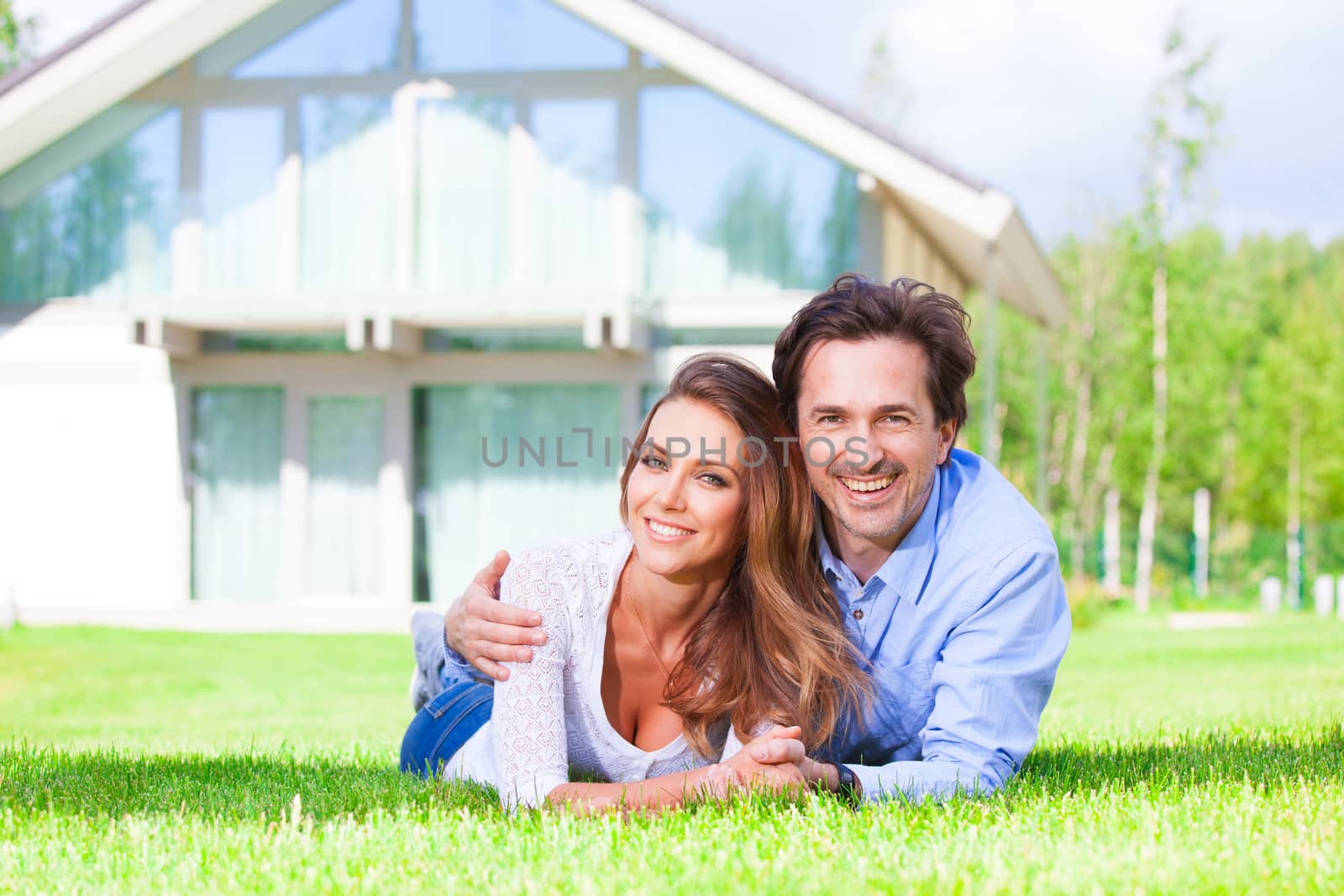 Happy couple laying in home garden by ALotOfPeople