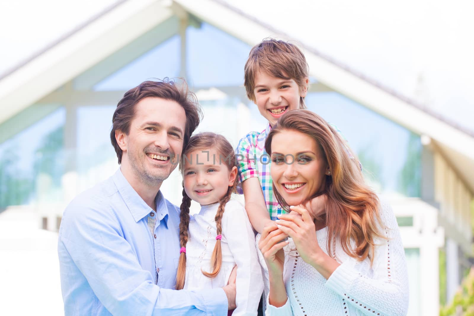 Happy family of parents and children in front of their house outdoors