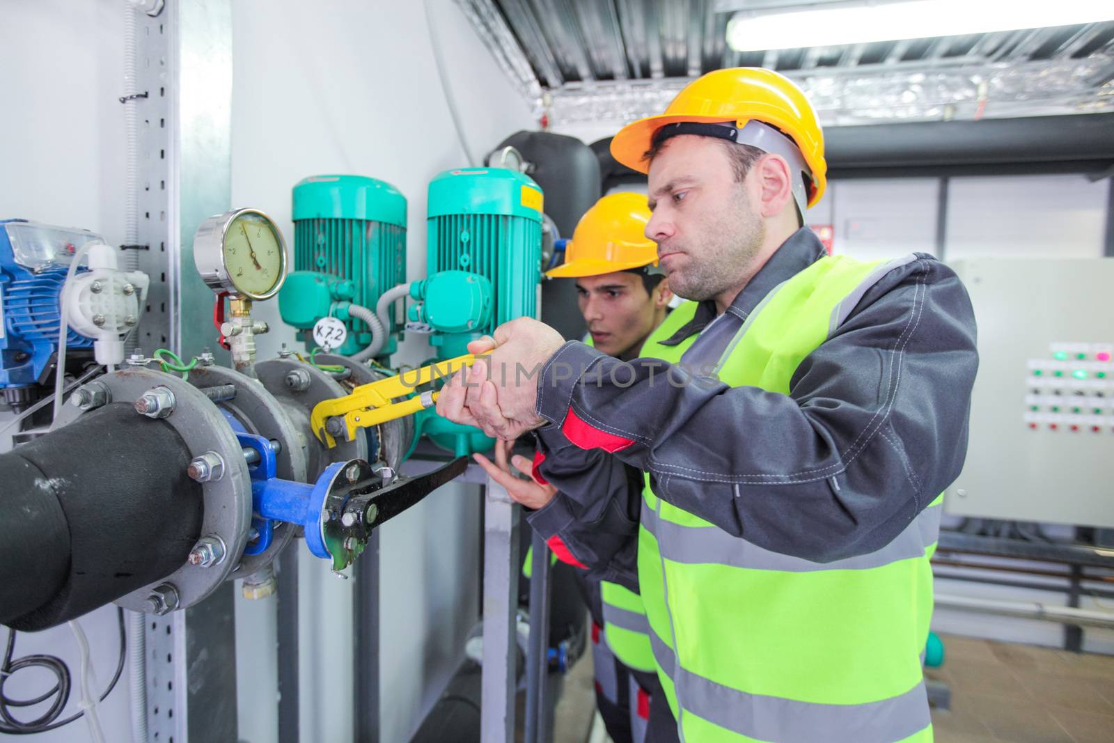 Two workers fixing pipes at factory by ALotOfPeople