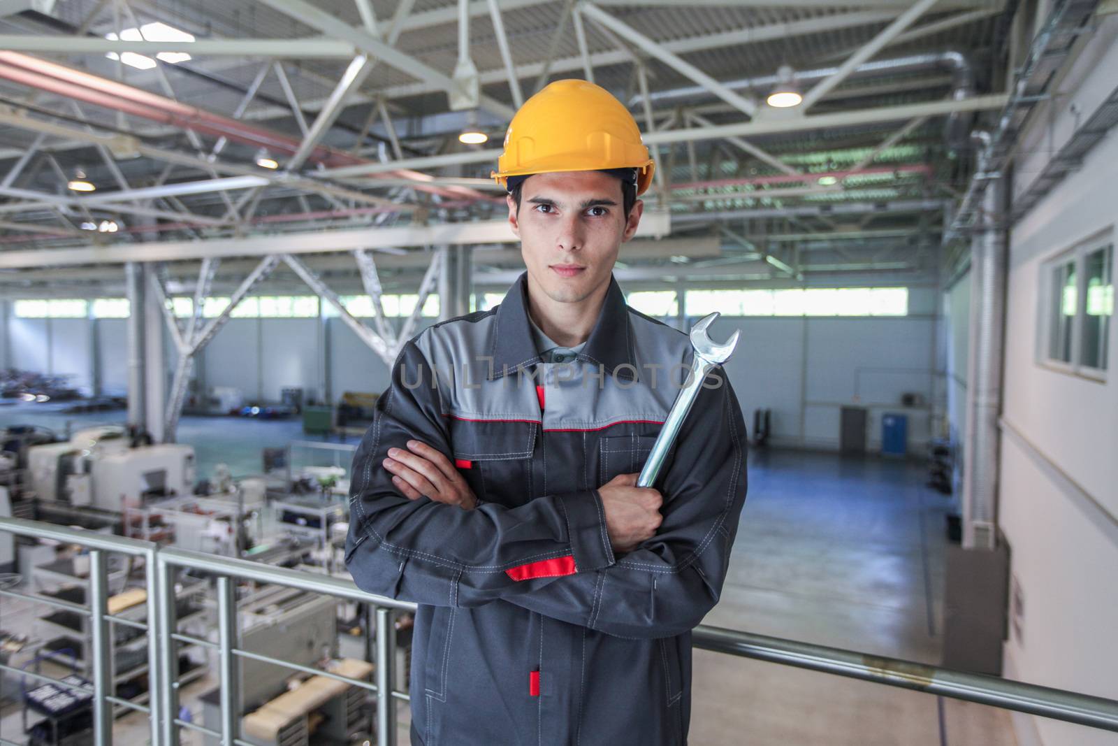 Young worker in hardhat with wrench at CNC factory