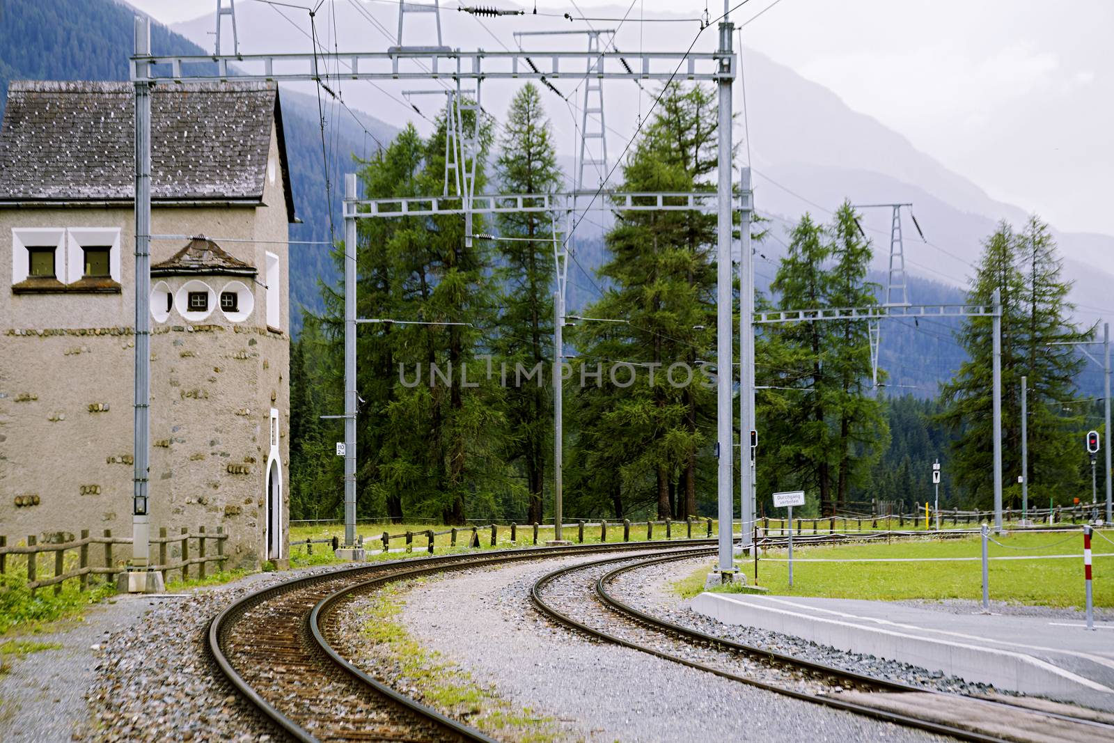 Old narrow gauge railway in the valley of the Alps among the trees in cloudy weather.