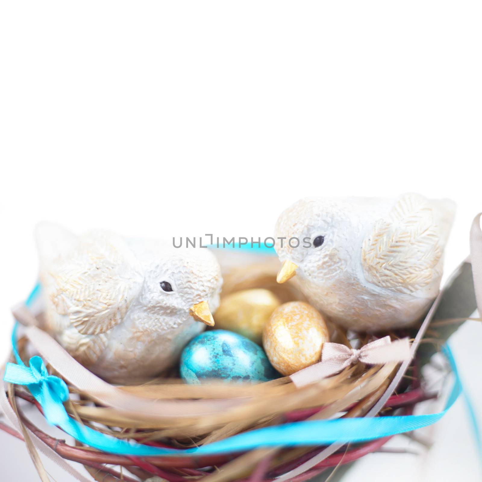Two cute handmade small easter birds and their golden eggs in nest , parenting , adoption , care concept . Isolated on white background , copy space for text