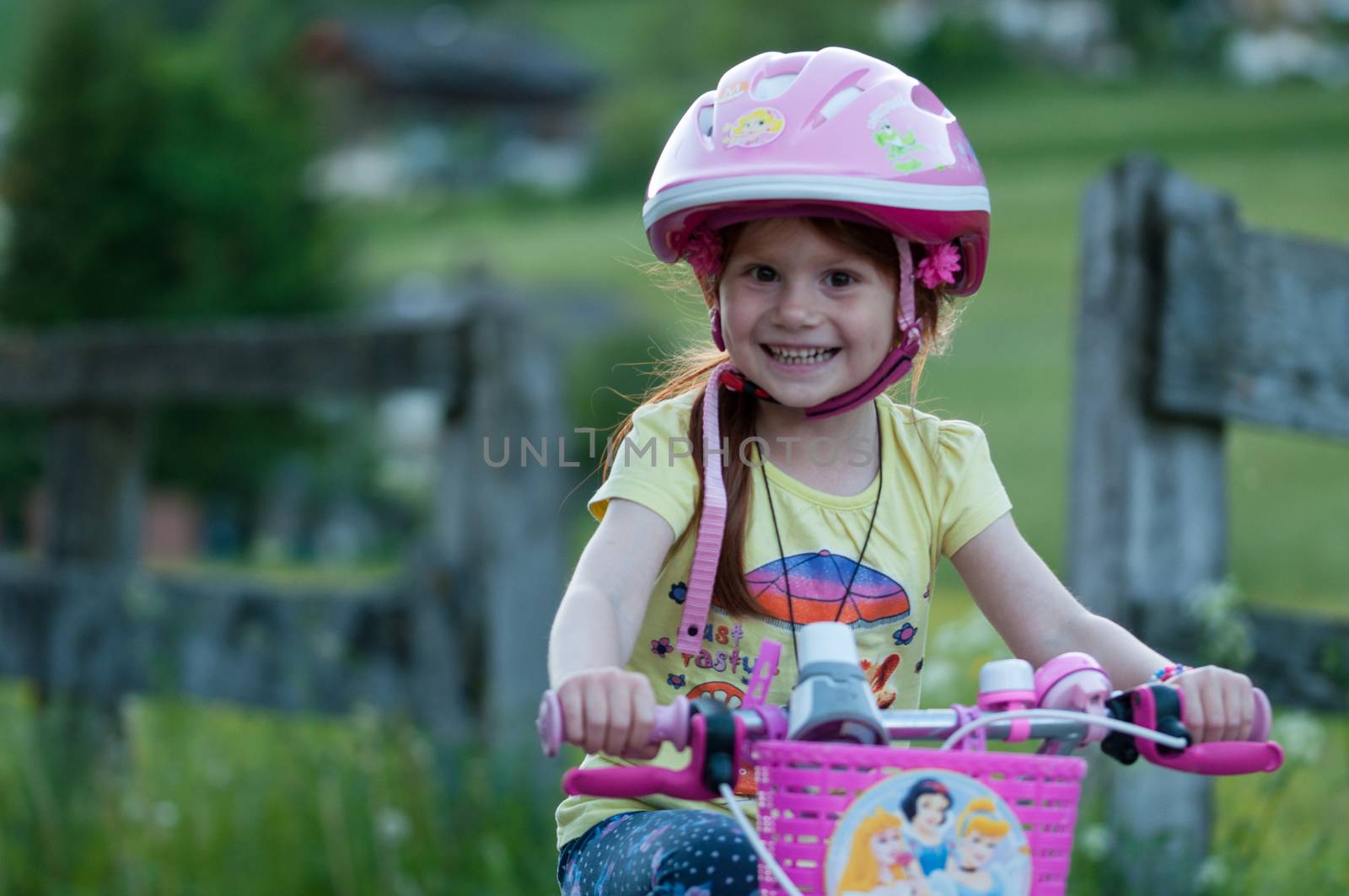 Little girl bicycling, background blurred,pink helmet