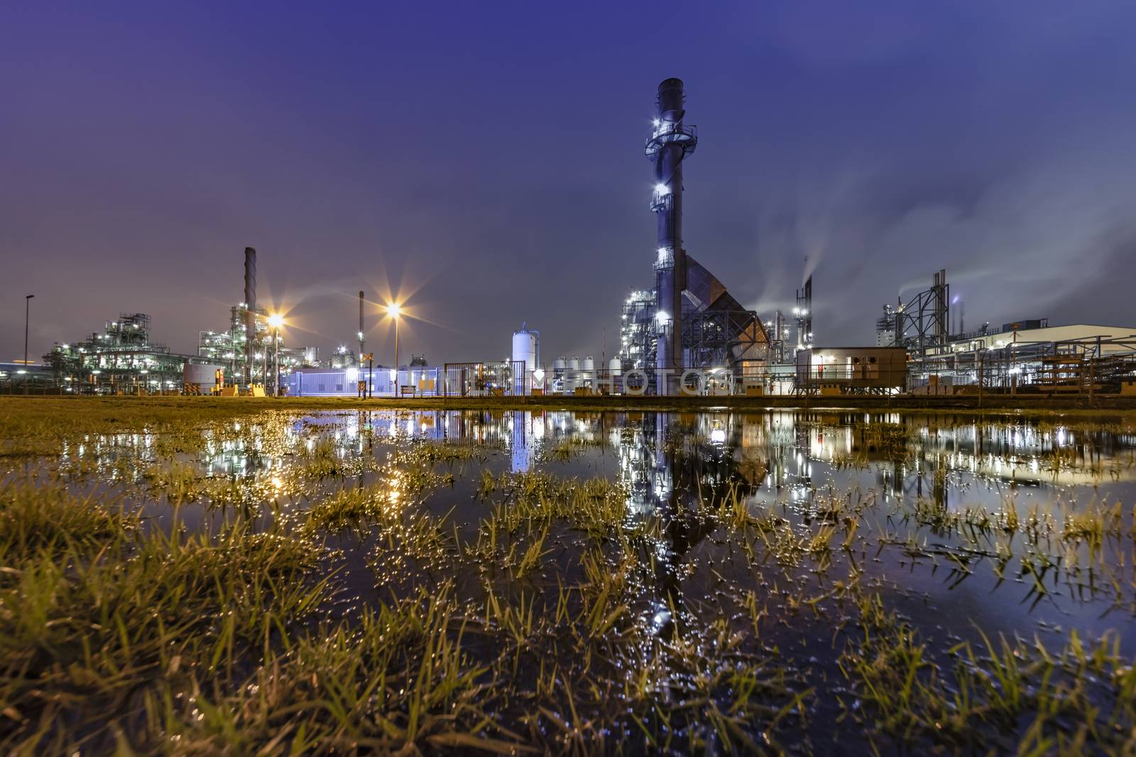 Reflection of the panorama of a refinery and its chimney during the sunset blue hour moment at Rotterdam, Netherlands