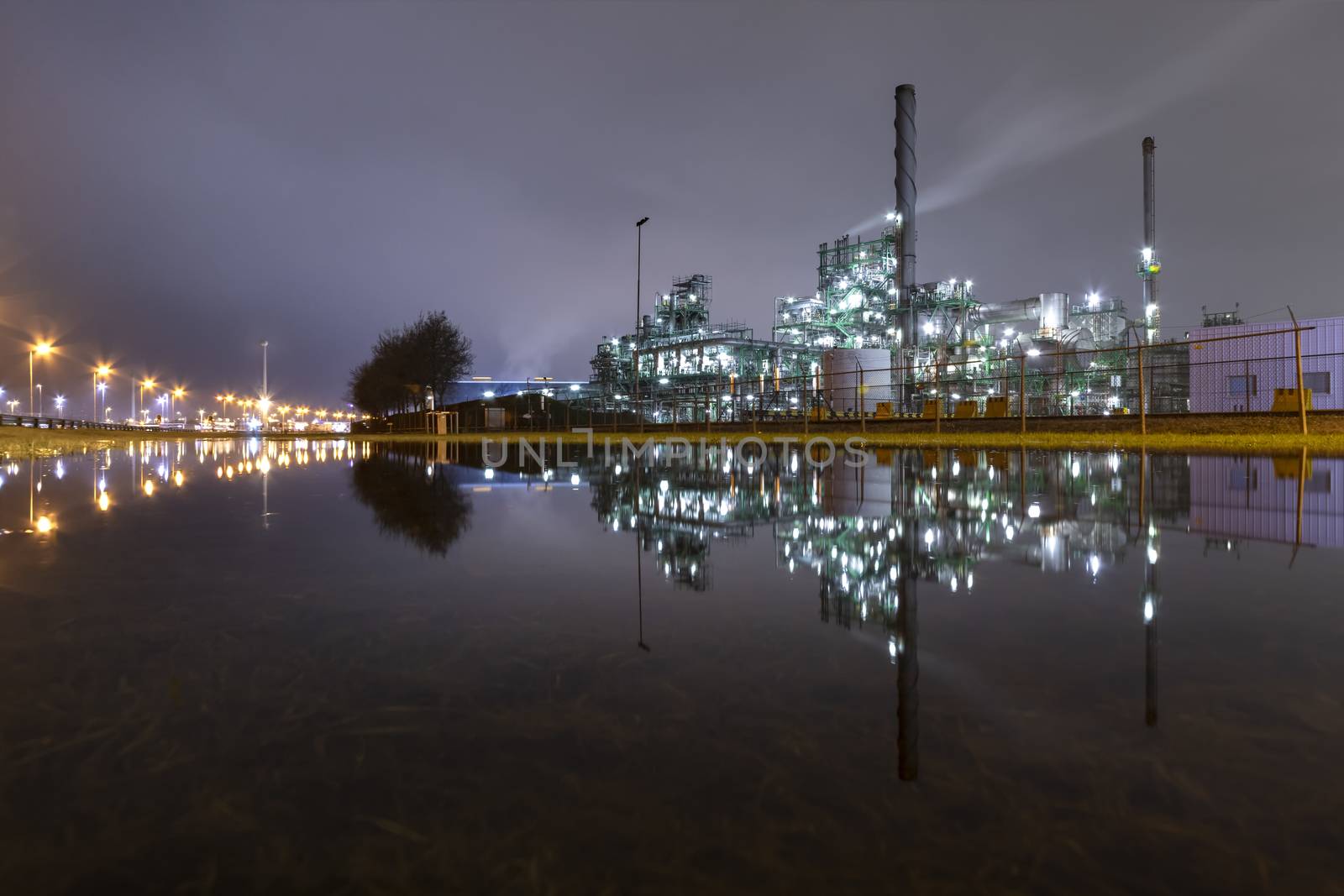 Reflection of the panorama of a refinery and its chimney during the sunset blue hour moment at Rotterdam, Netherlands by ankorlight