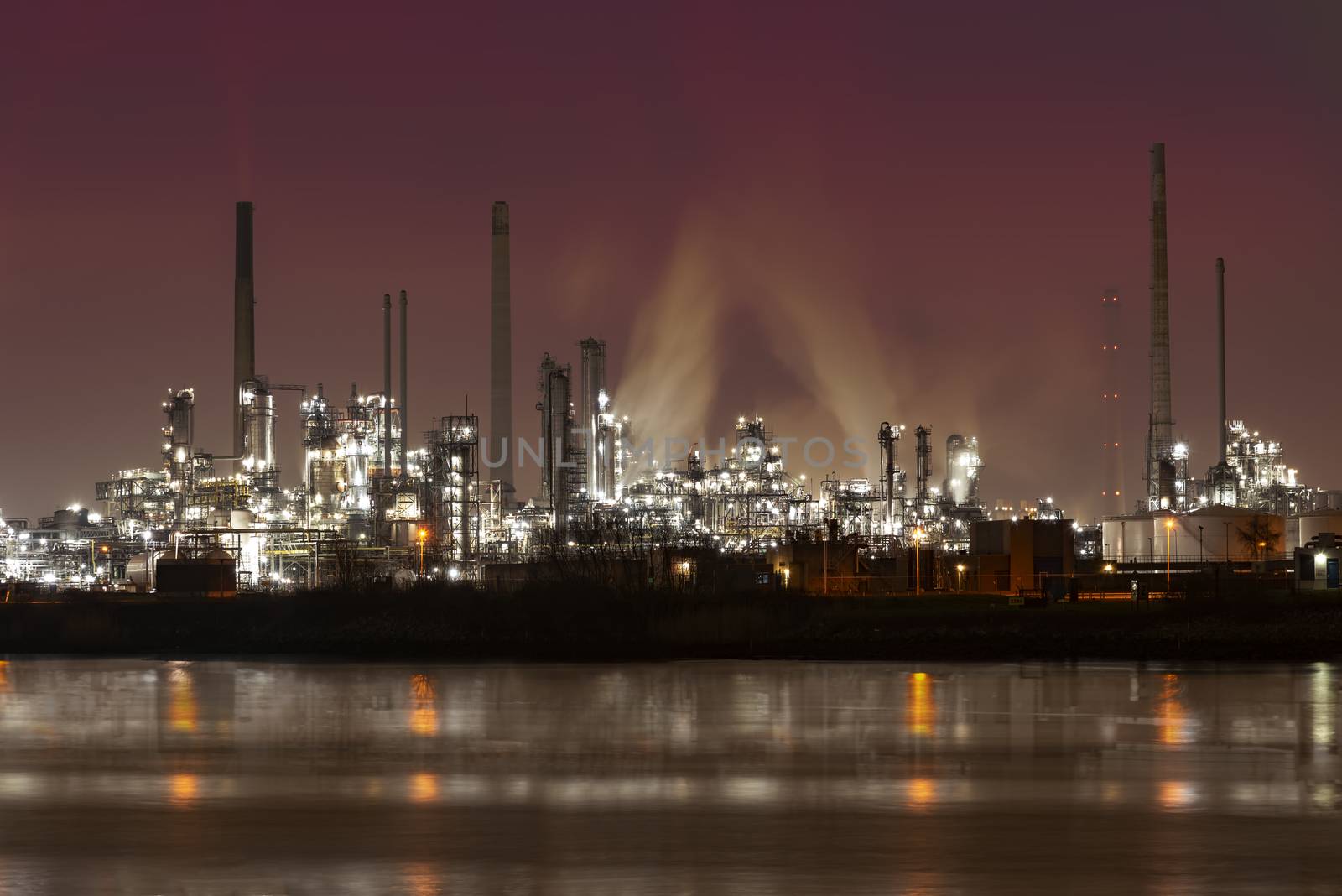 Reflection of refineries and its chimney during the on fire sunset golden hour moment at Rotterdam, Netherlands by ankorlight