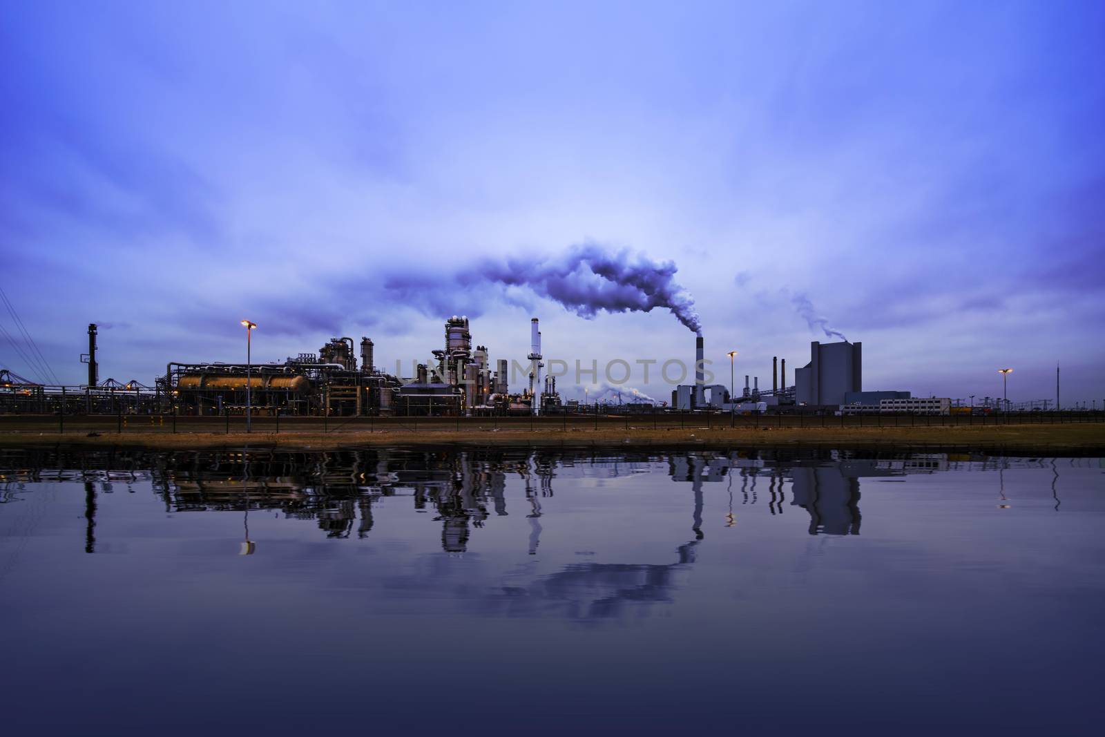 Reflection of refineries and its chimney during the on blue sunset hour moment at Rotterdam, Netherlands