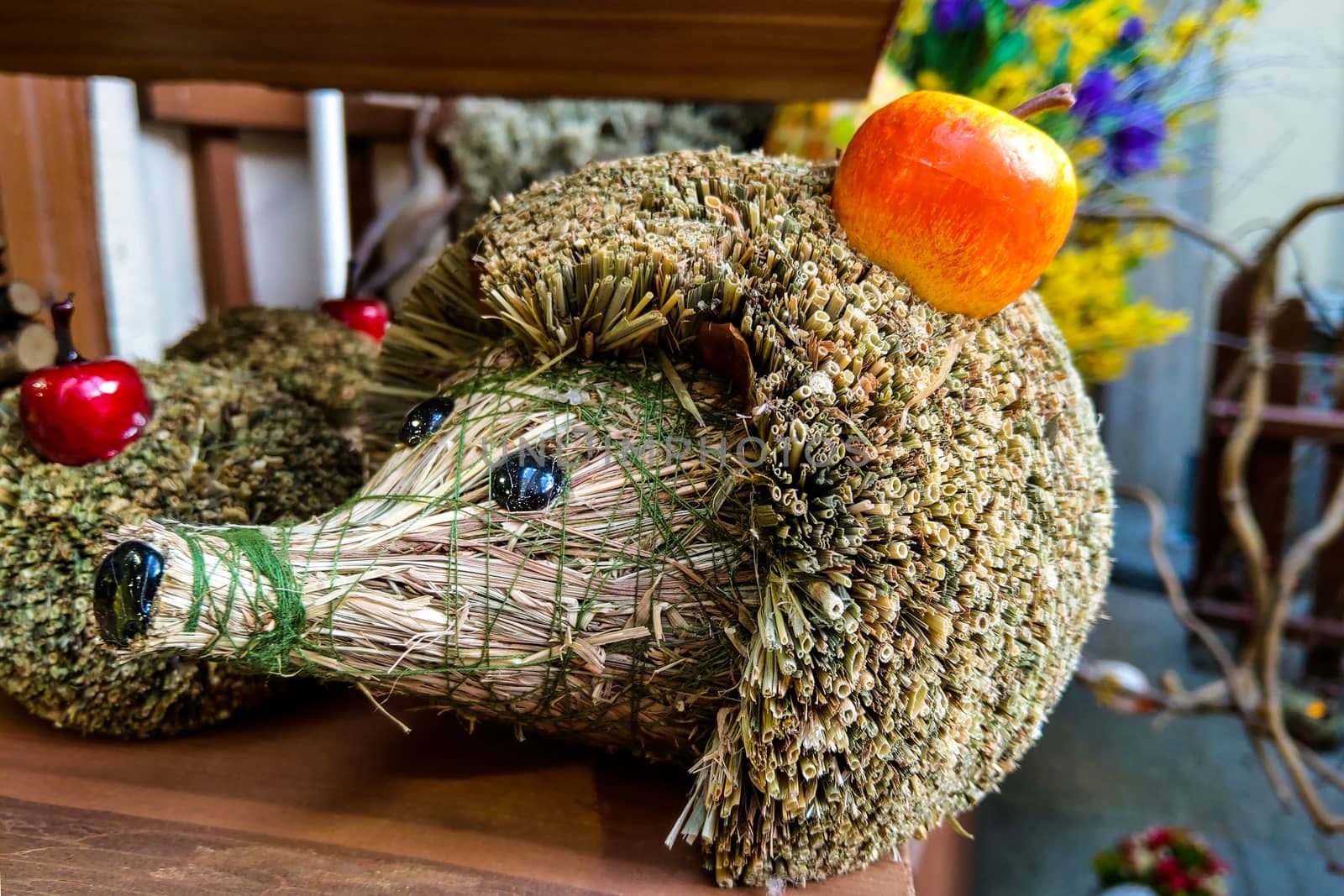 Beautiful decorative hedgehog made of straw with an apple