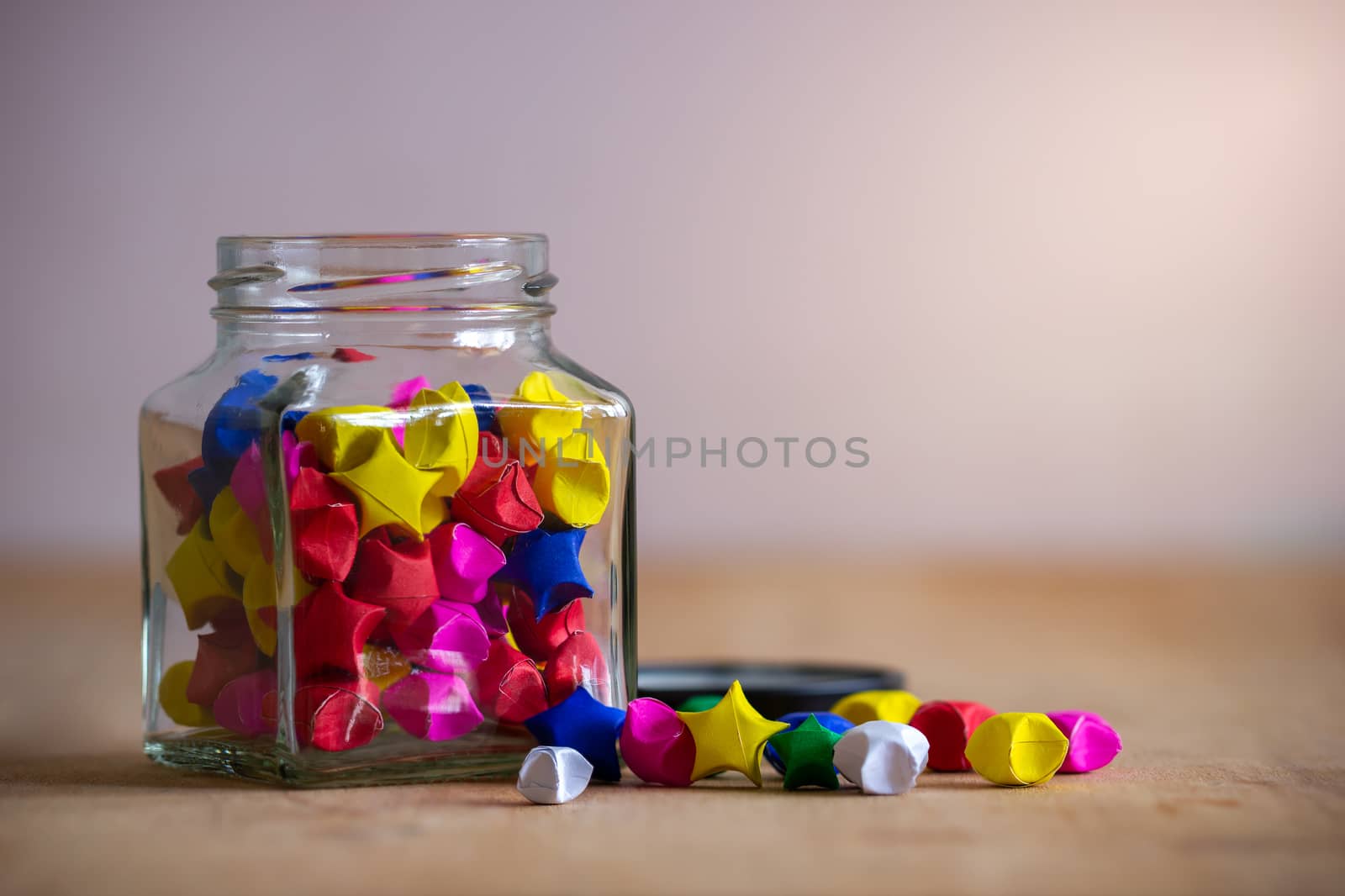 Multicolor paper star in square glass bottle on wooden table wit by SaitanSainam