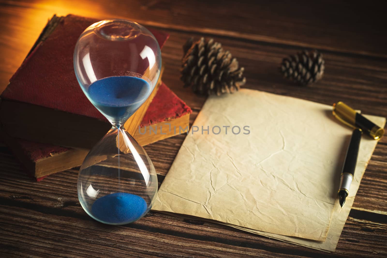 Hourglass and old books with old paper and pen on wooden tables  by SaitanSainam