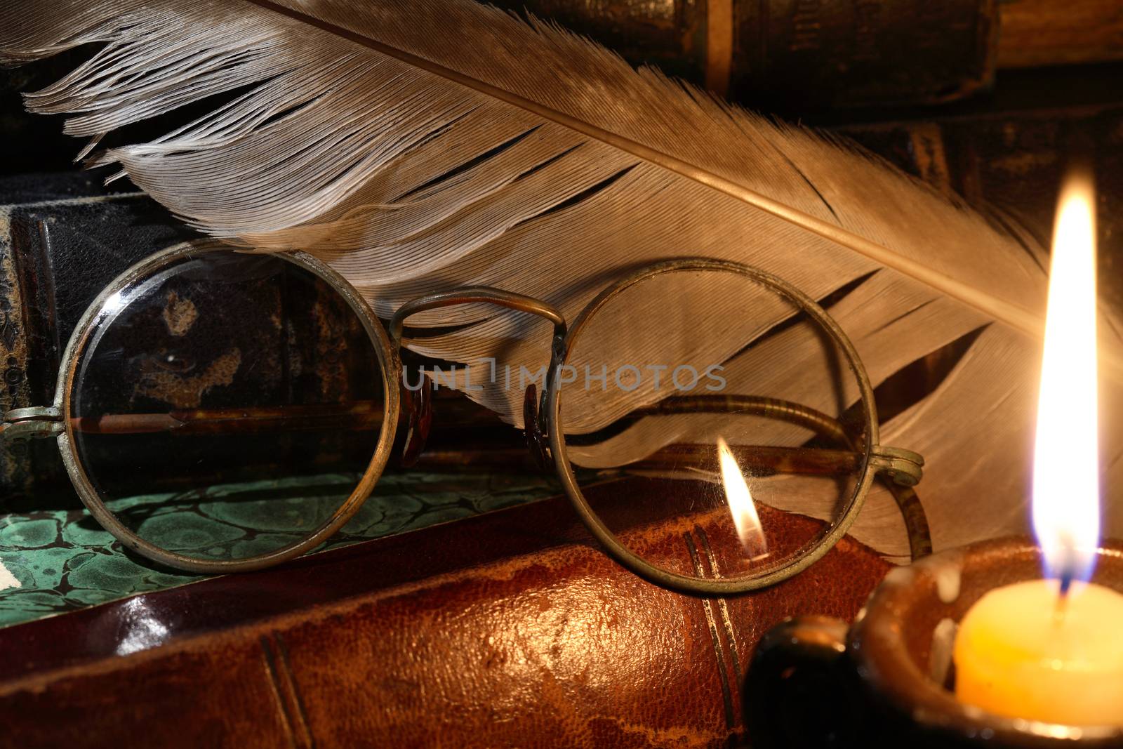 Vintage still life with old glasses against lighting candle and books