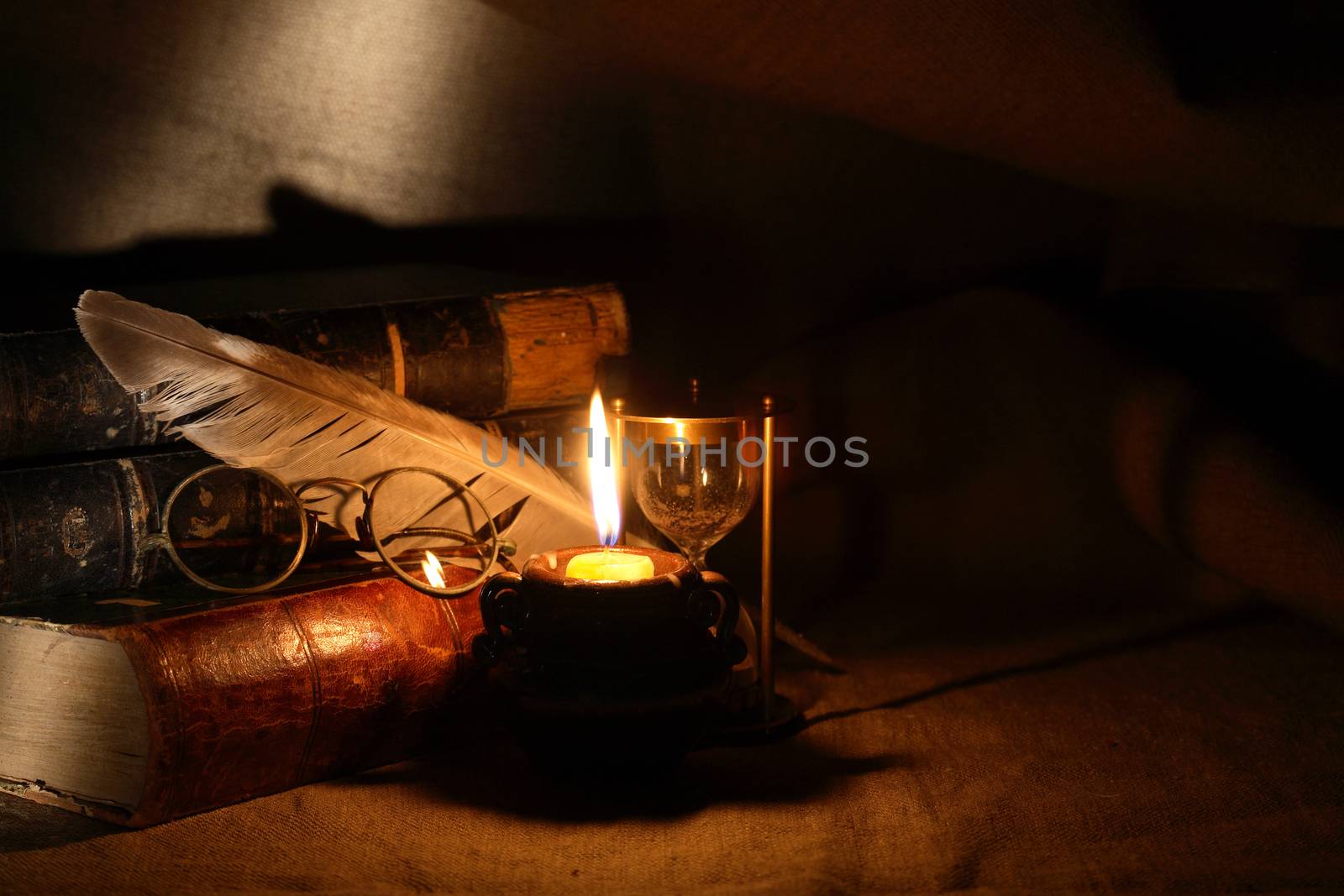 Vintage still life with old glasses against lighting candle and books