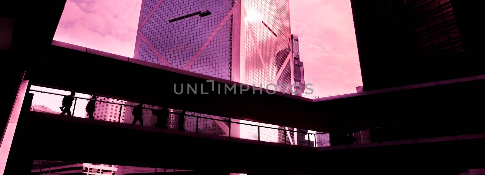 A group of people is walking on a high passage against the backdrop of modern buildings. Blurred motion. Silhouette.