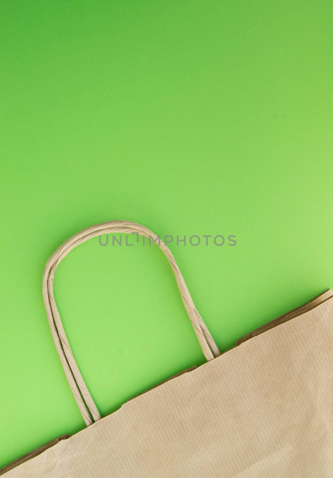 Concept of zero waste, reusable paper bag for shopping, free plastic, green background, top view, vertical photo by claire_lucia