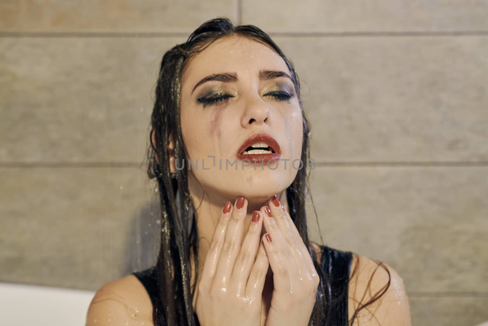 Young woman portrait with dripping smeared makeup dressed in the black bathing suit posing in the bathroom. Conceptual fashion photography for design. Young woman for lifestyle design.