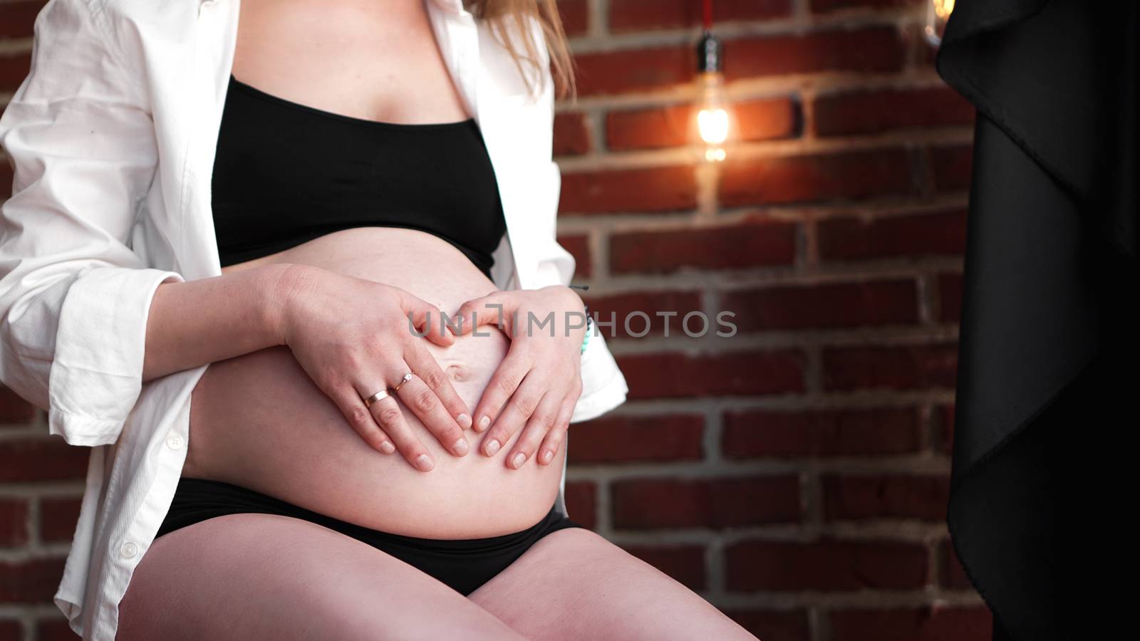 Pregnant Woman holding her hands in a heart shape on her baby bump by natali_brill