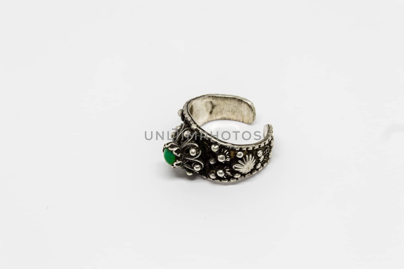 a closeup shoot to antique silver ring with green stone on it, white background.