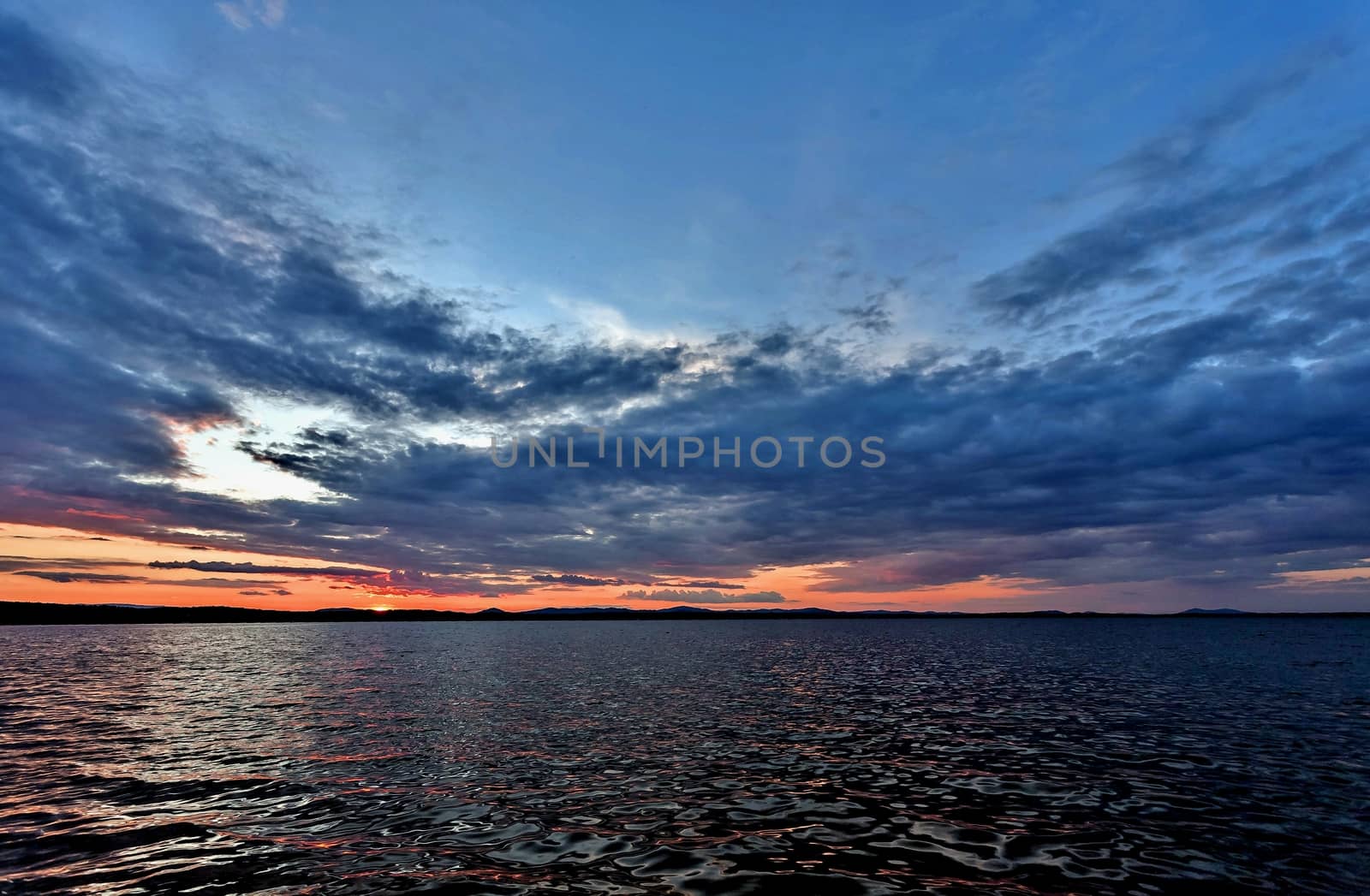 dark blue evening sky over the lake, orange sun by valerypetr
