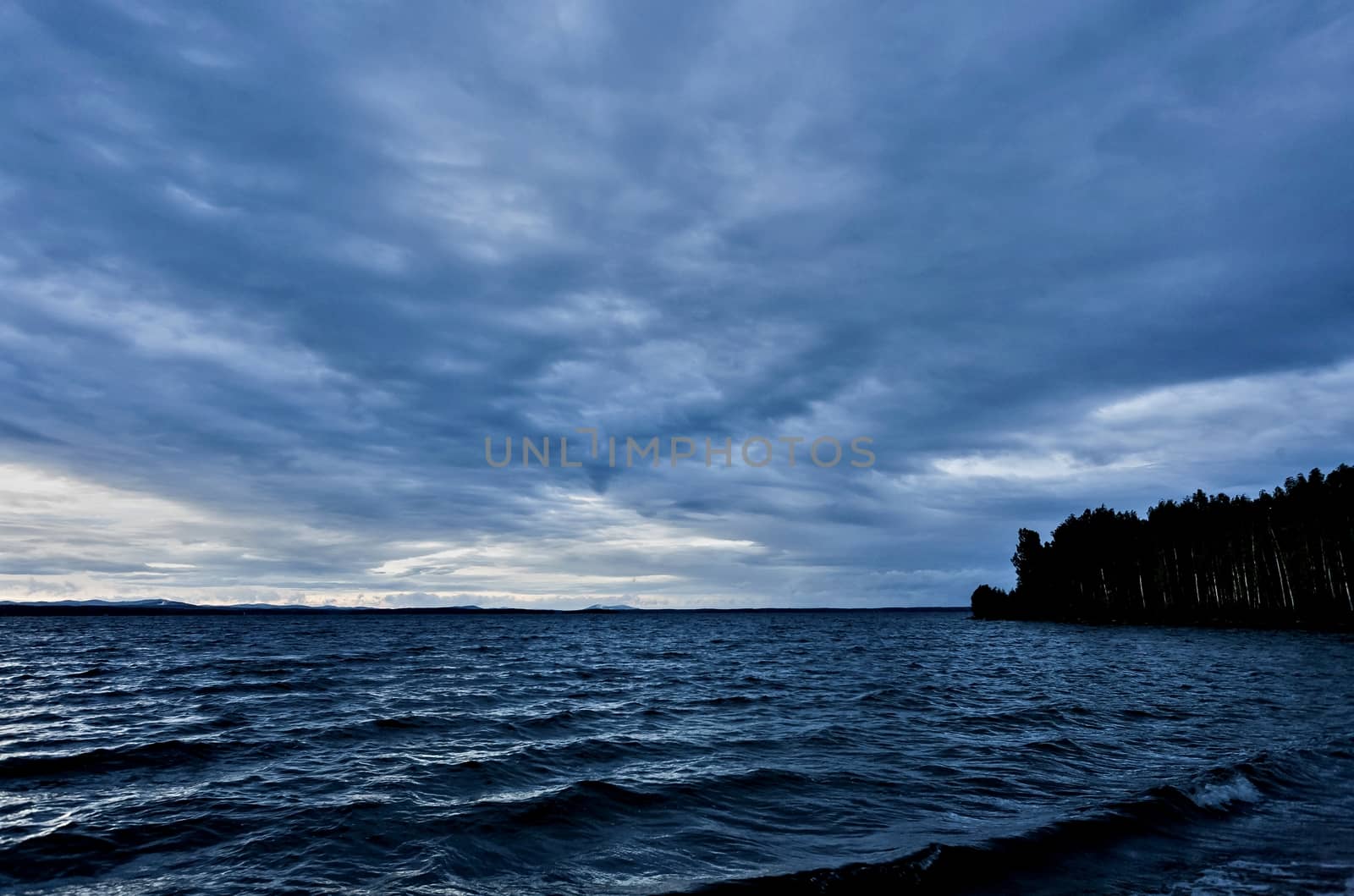 dark blue evening cloudy sky over the lake by valerypetr