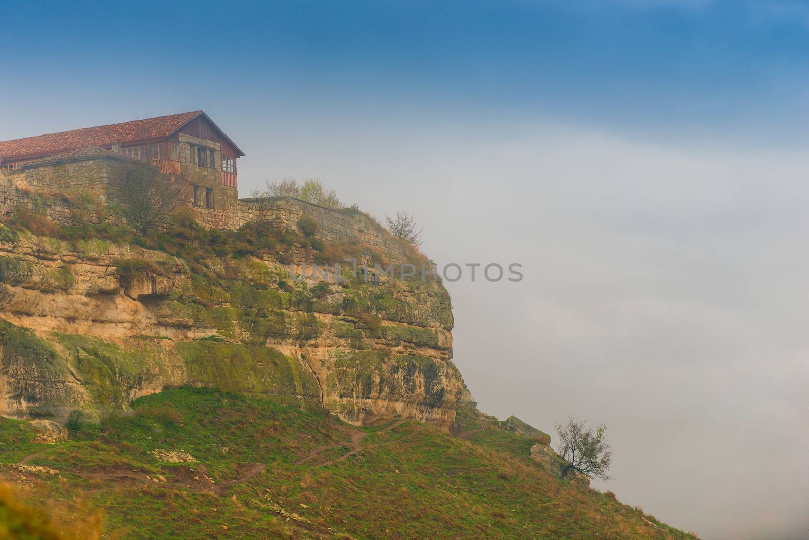 View of the cliff with the buildings of the ancient city of Chufut-Kale on a foggy autumn day, Crimea, Russia