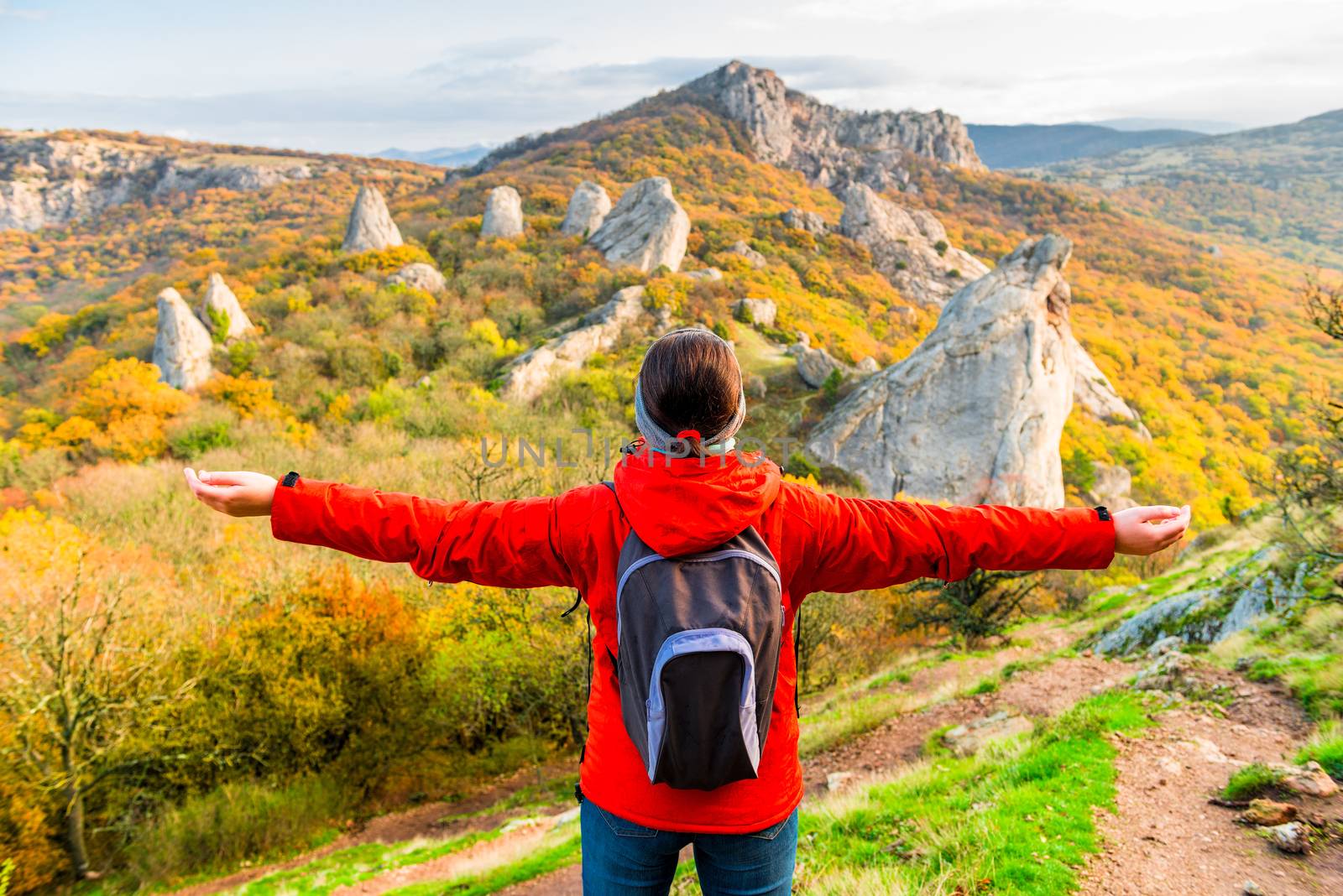 Woman Tourist with a backpack with open arms enjoying the autumn landscape in the mountains