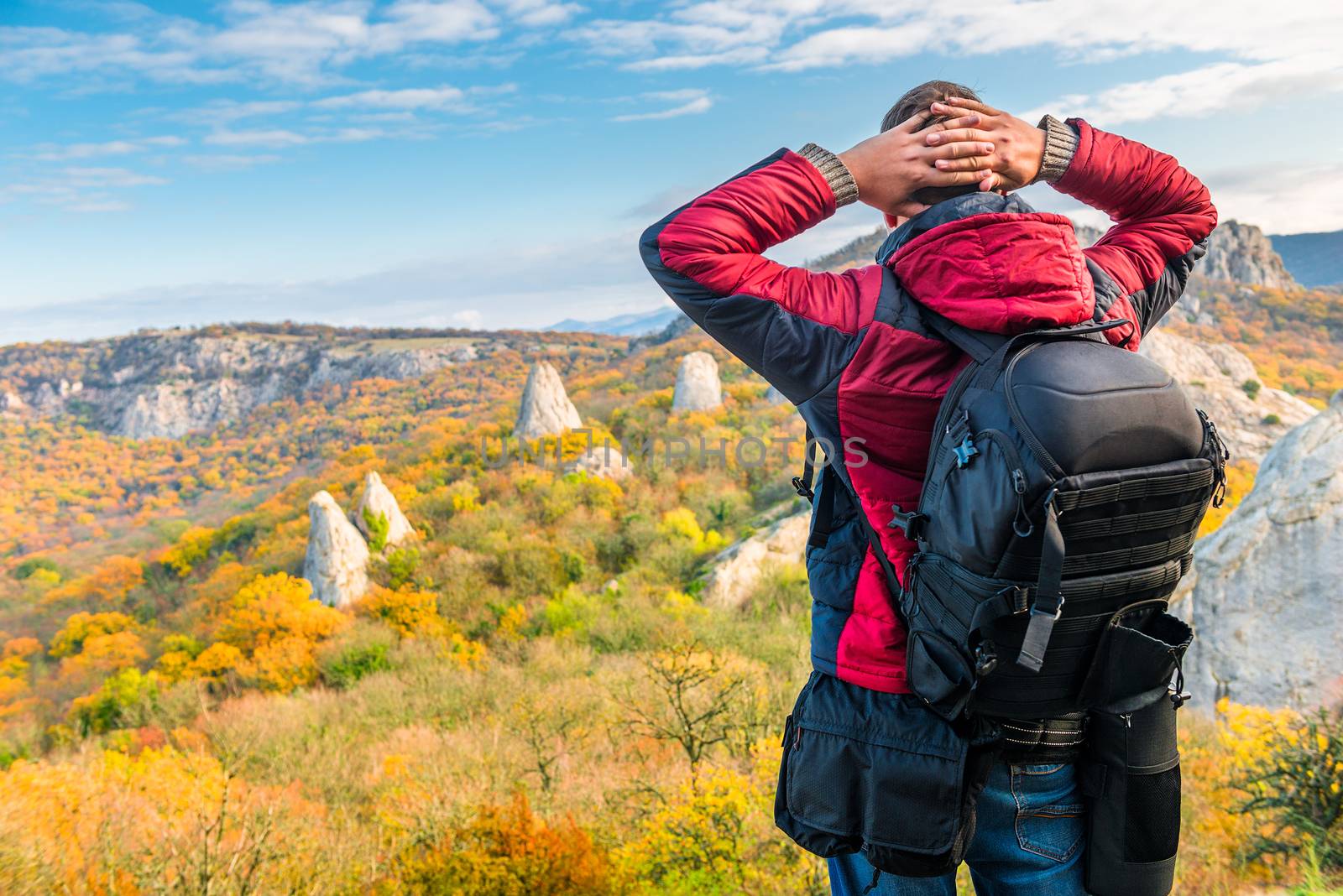 Photographer traveler with a backpack admiring beautiful mountains in autumn, rear view