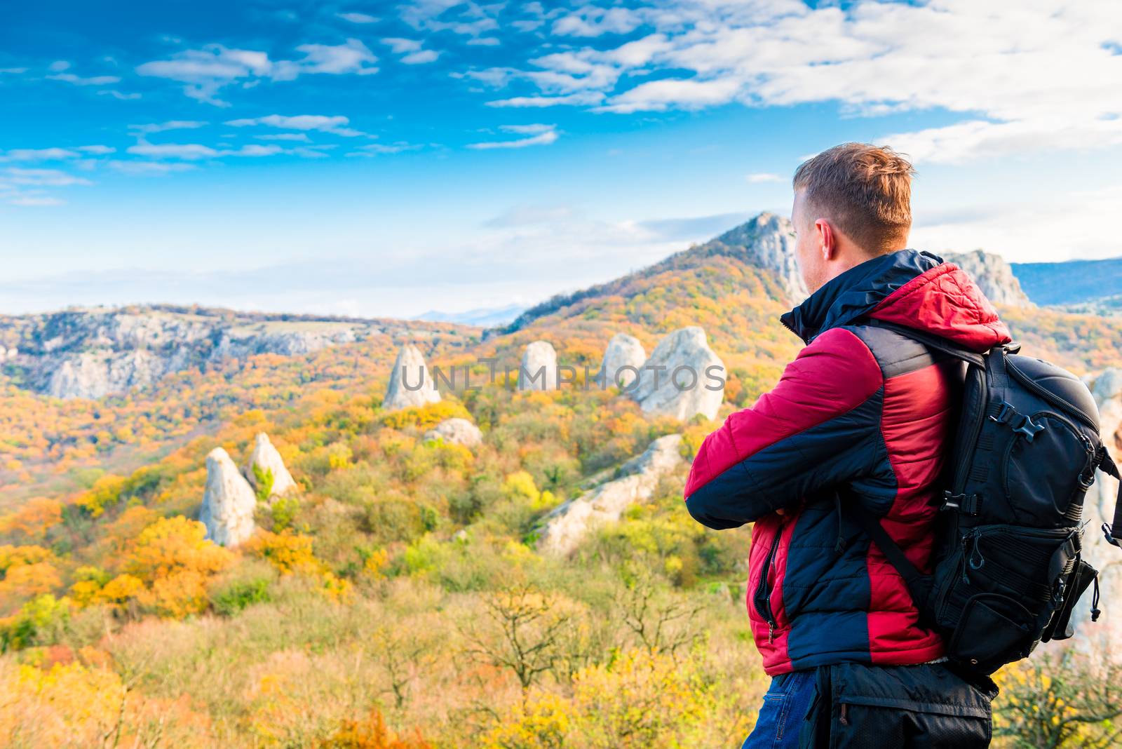 Photographer traveler with a backpack admiring the beautiful mountains in autumn