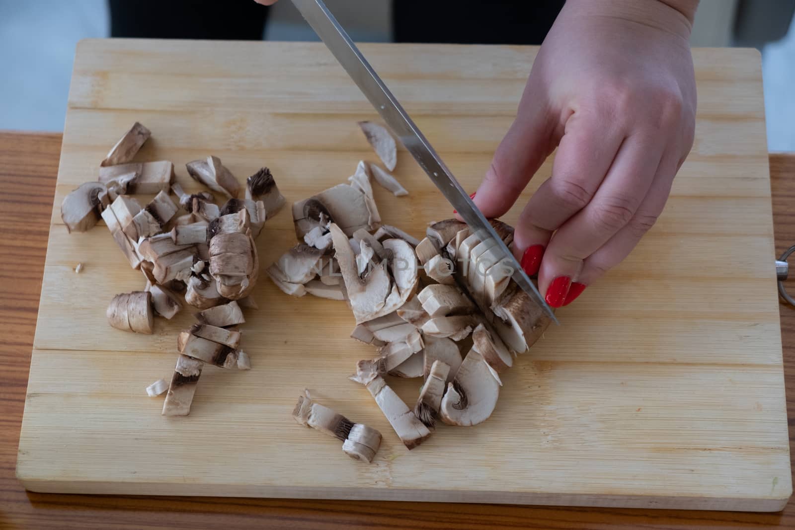 Woman cutting mushrooms on wooden board by rdv27